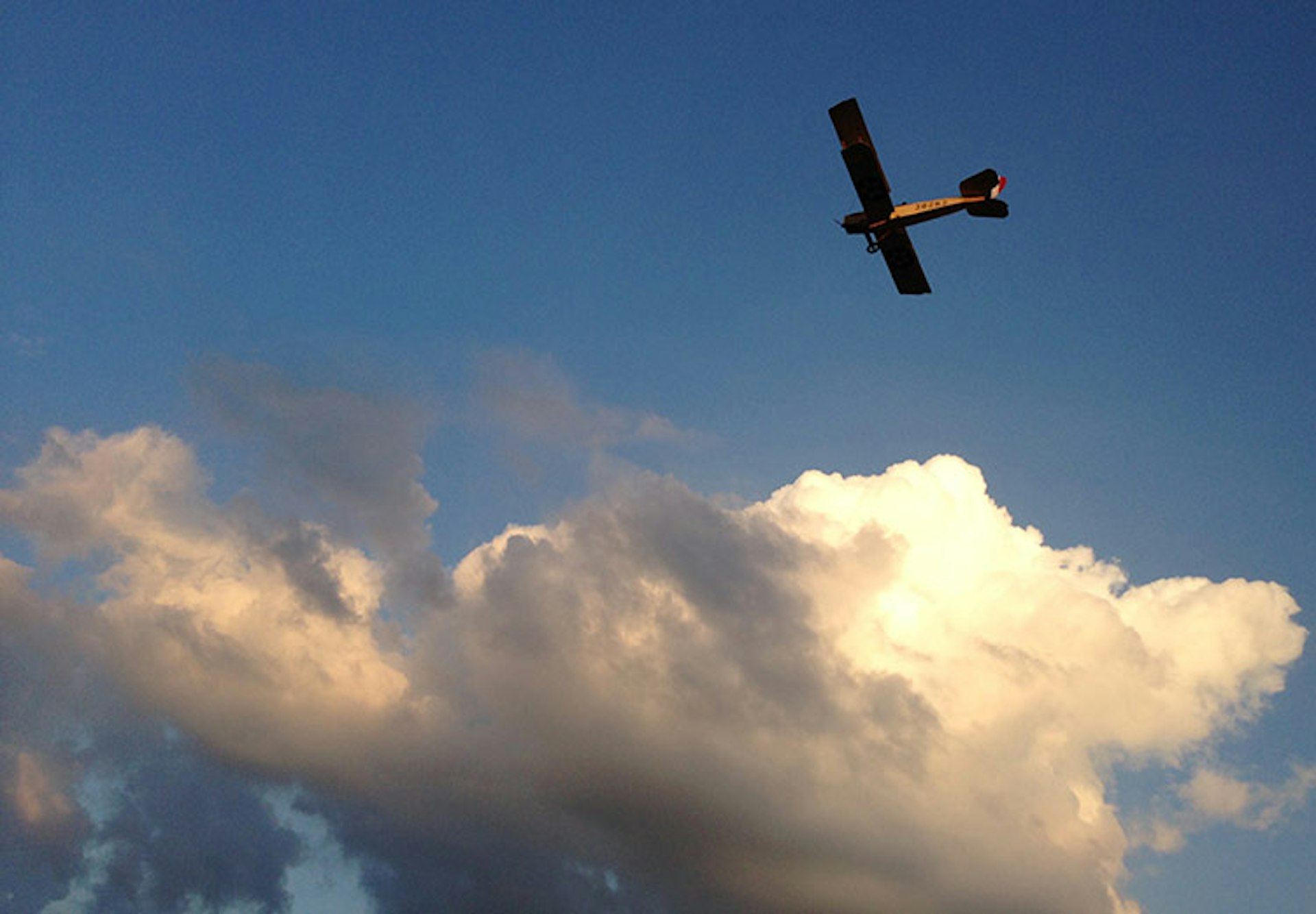 The restored Curtiss Jenny soars above the clouds. Image courtesy of Friends of Jenny
