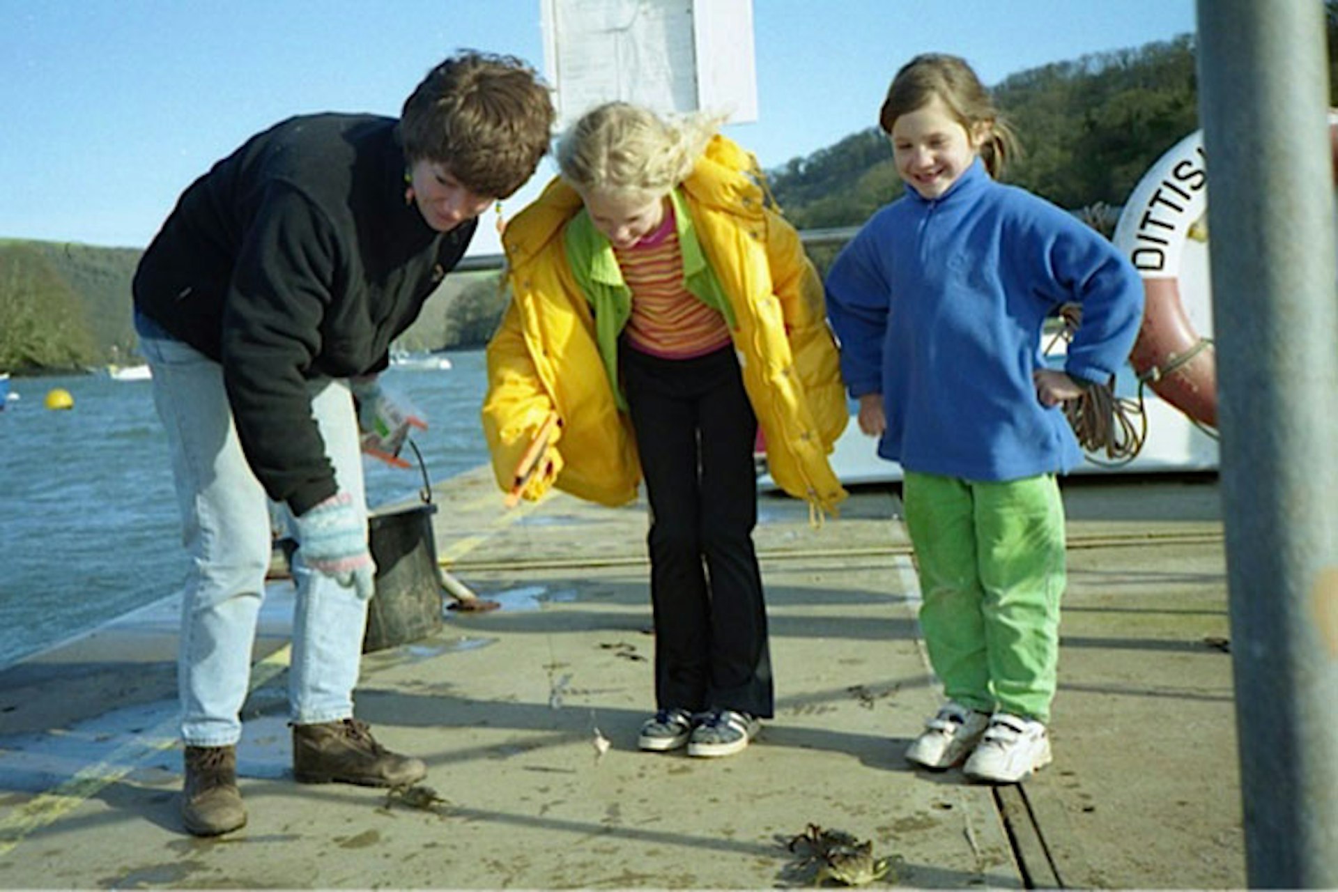 Ellie Simpson (centre) inspects the day’s catch on a jetty in Devon. Image by Ellie Simpson / Lonely Planet.