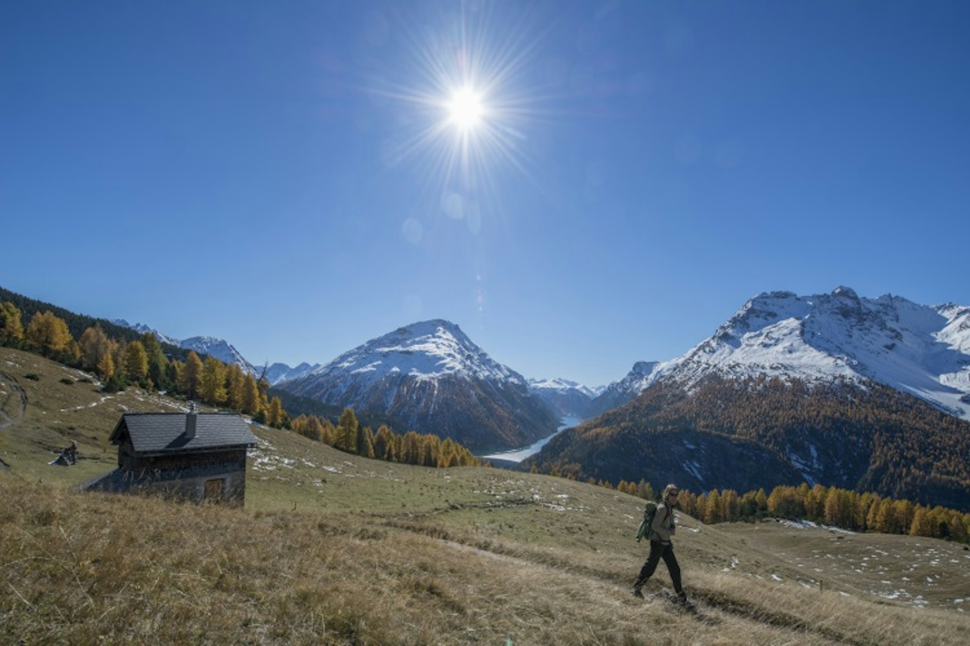 A hiker sets off under the sun on Alp la Schera. Image courtesy of the Swiss National Park.