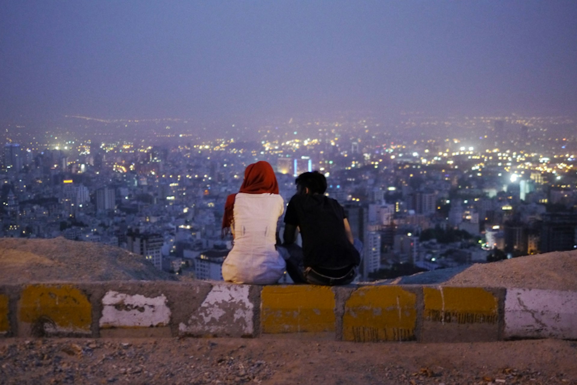 A young couple admire the view of Tehran at dusk. Image by Amos Chapple / Lonely Planet Images / Getty