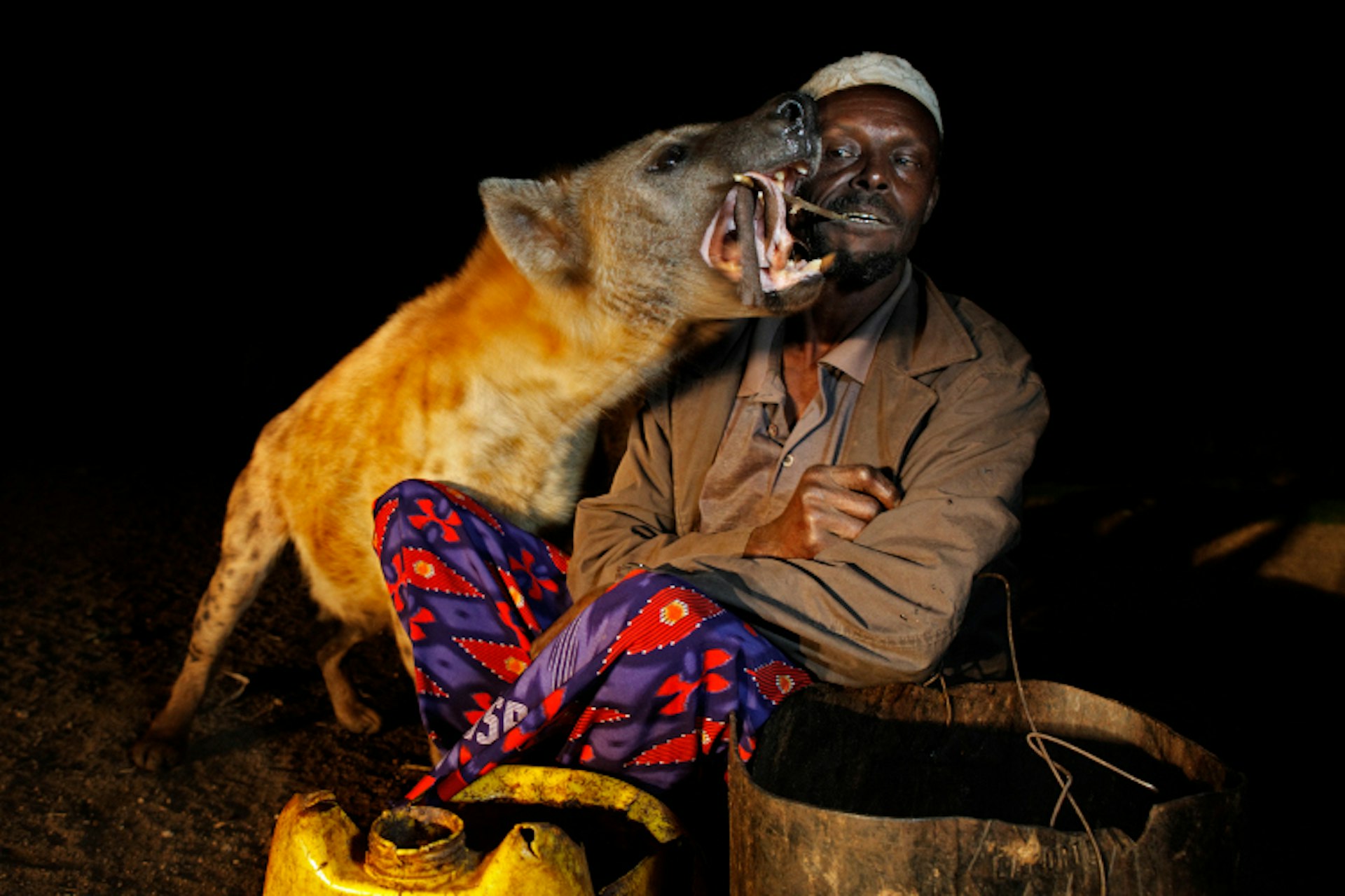 A man feeds a hyena in Harar with a stick straight from his mouth. Image by Johnny Haglund / Lonely Planet Images / Getty