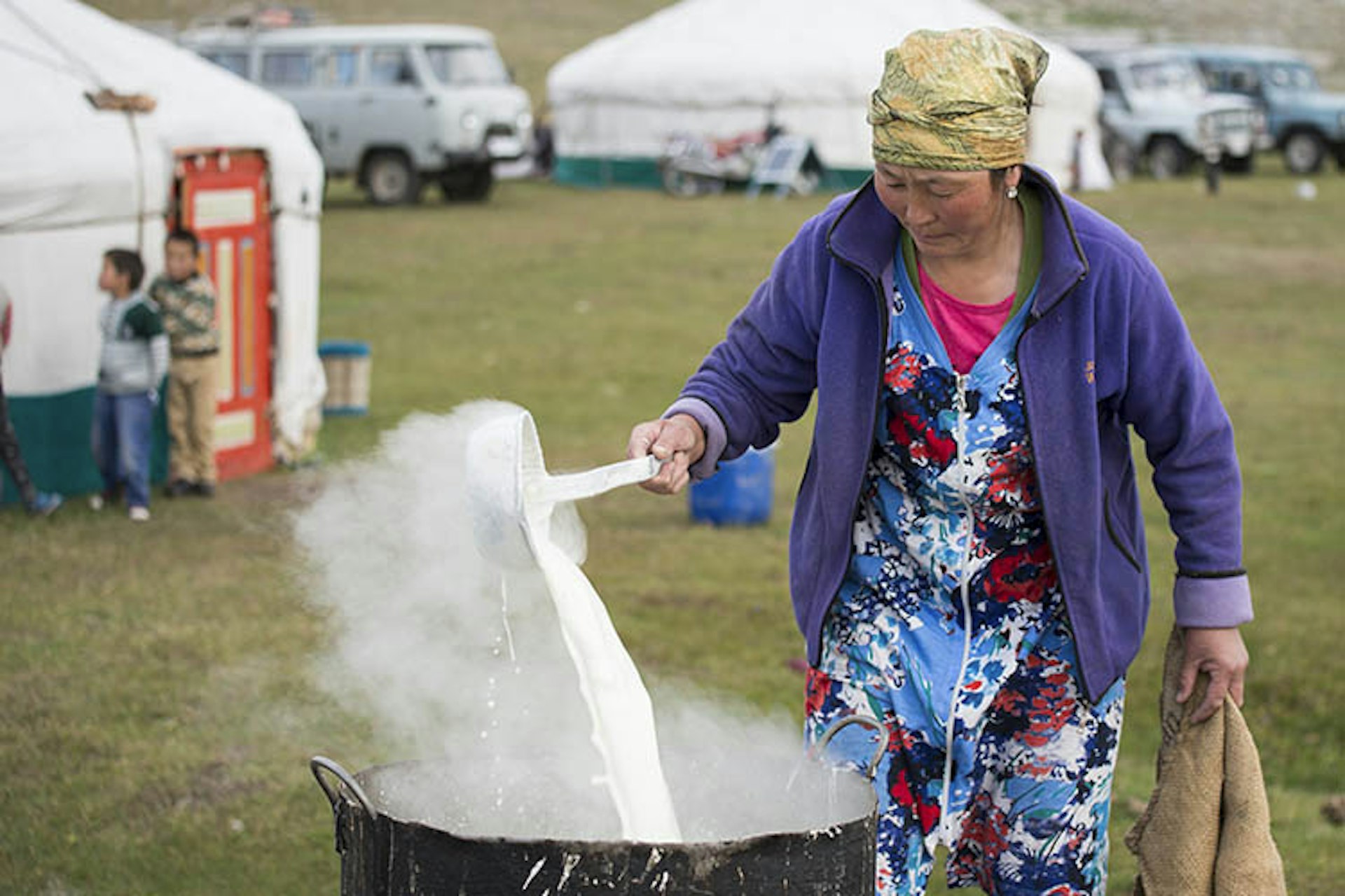 A Kazakh woman churns milk over a fire to make cheese. Image by David Baxendale / Lonely Planet