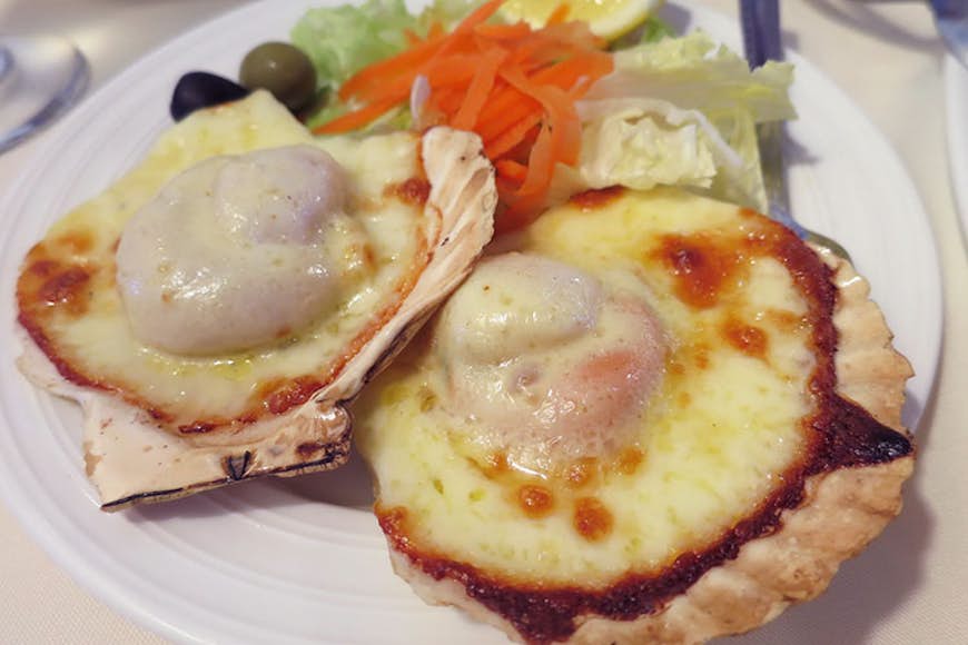 Cheesy baked scallops. Image by Megan Eaves / Lonely Planet