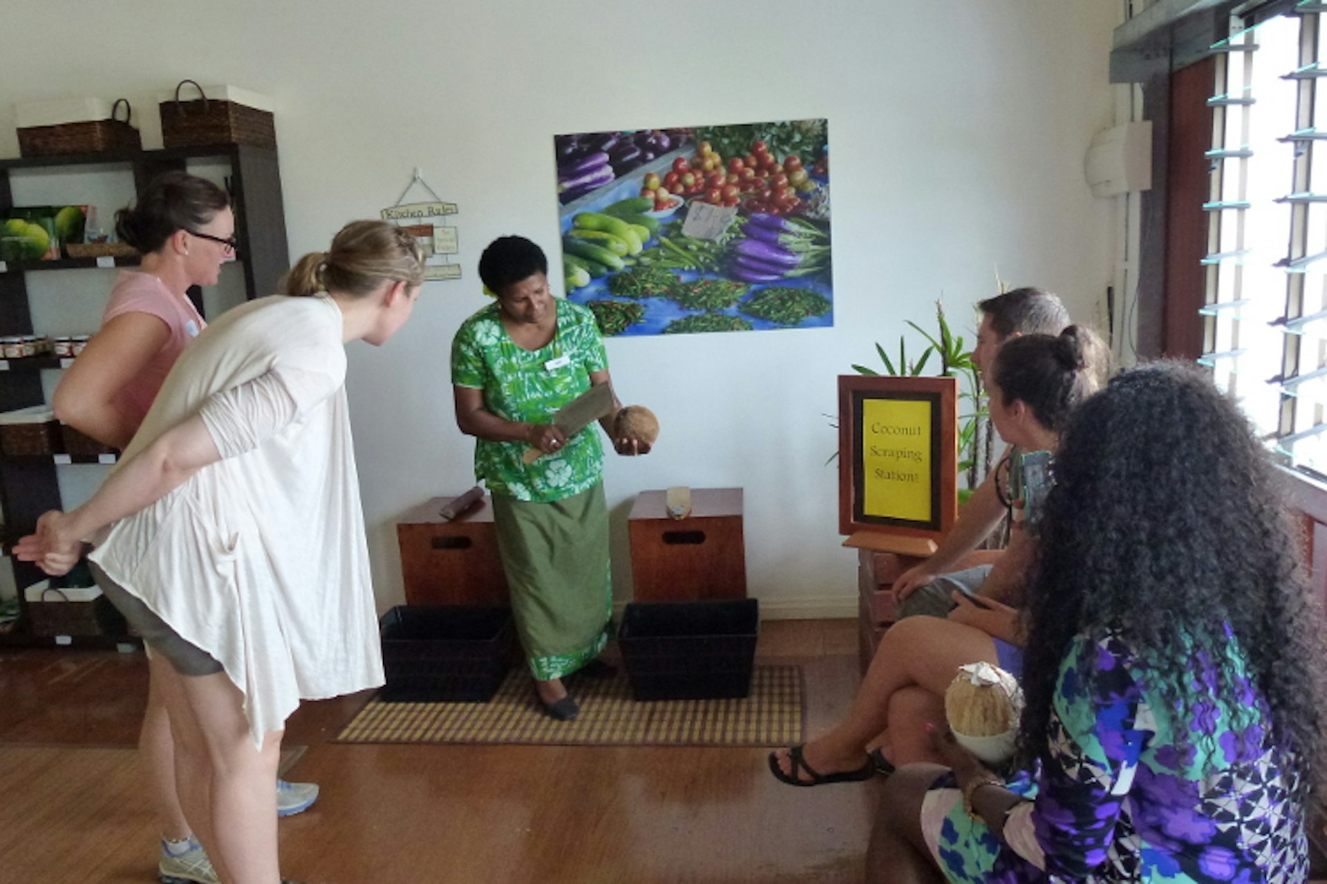 Demonstrating how to scrape a coconut. Image by Flavours of Fiji Cooking School