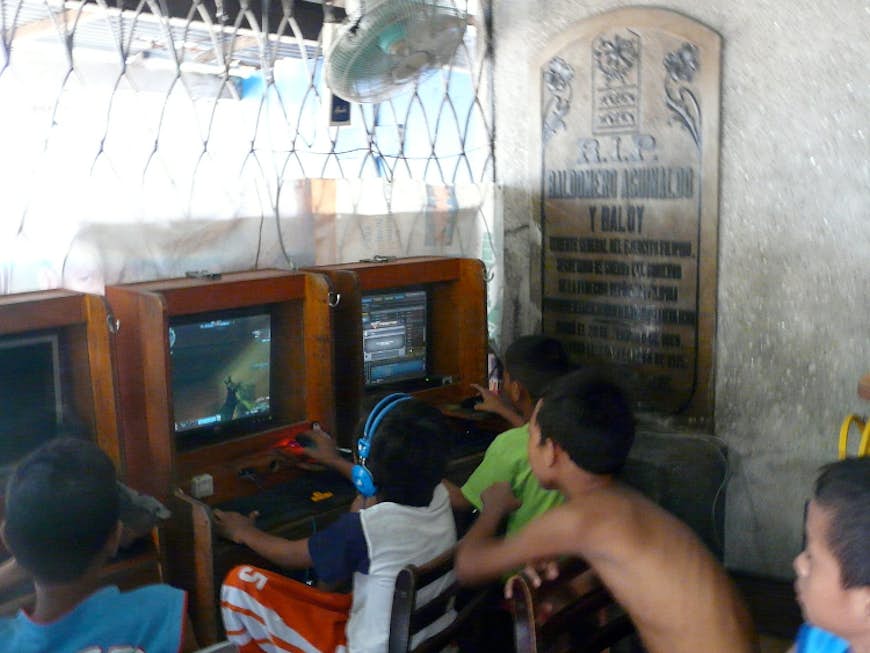 Children play in a makeshift arcade in the North Cemetery, Manila