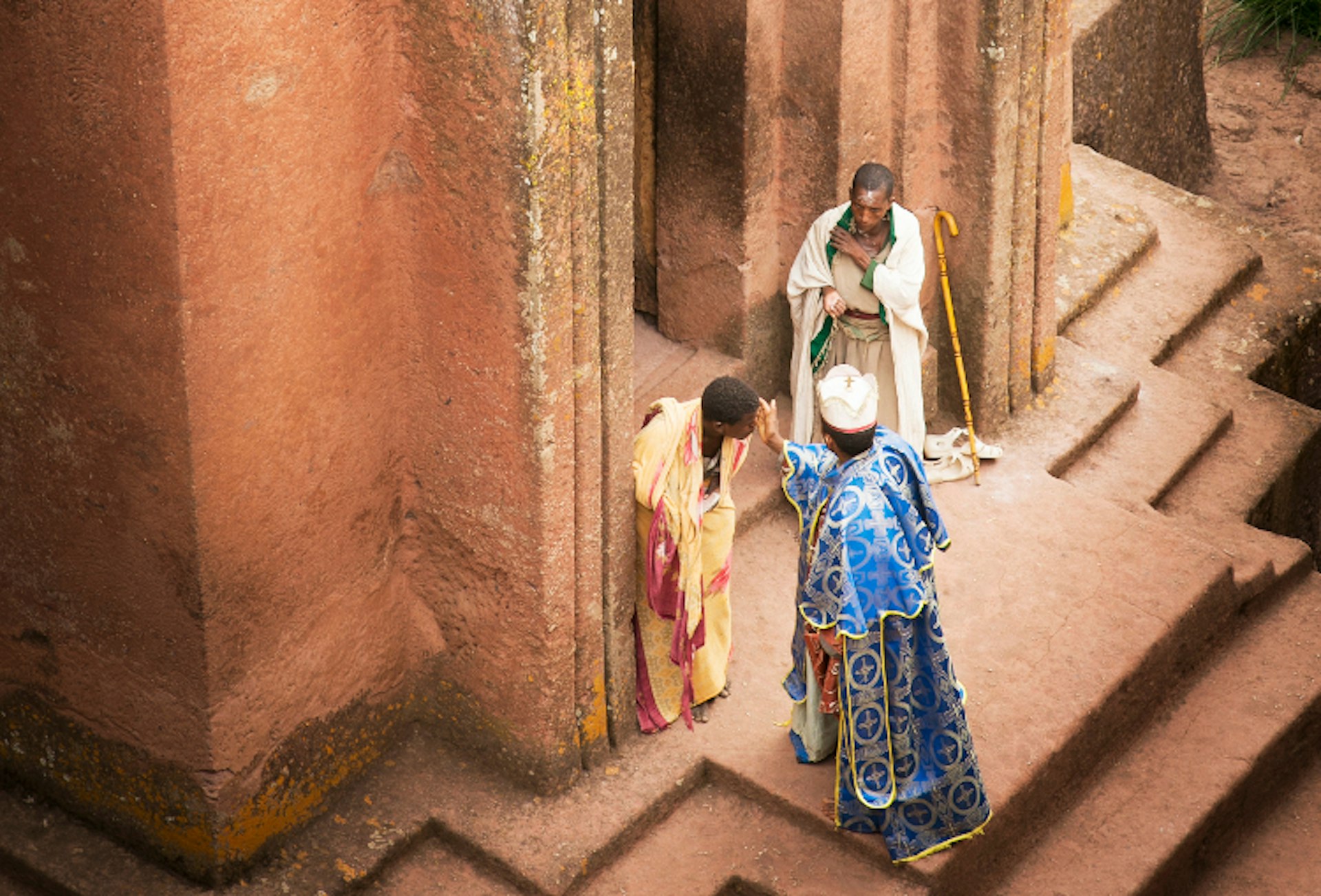 A priest blesses pilgrims outside the entrance to Bet Giyorgis. Image by Philip Lee Harvey / Lonely Planet