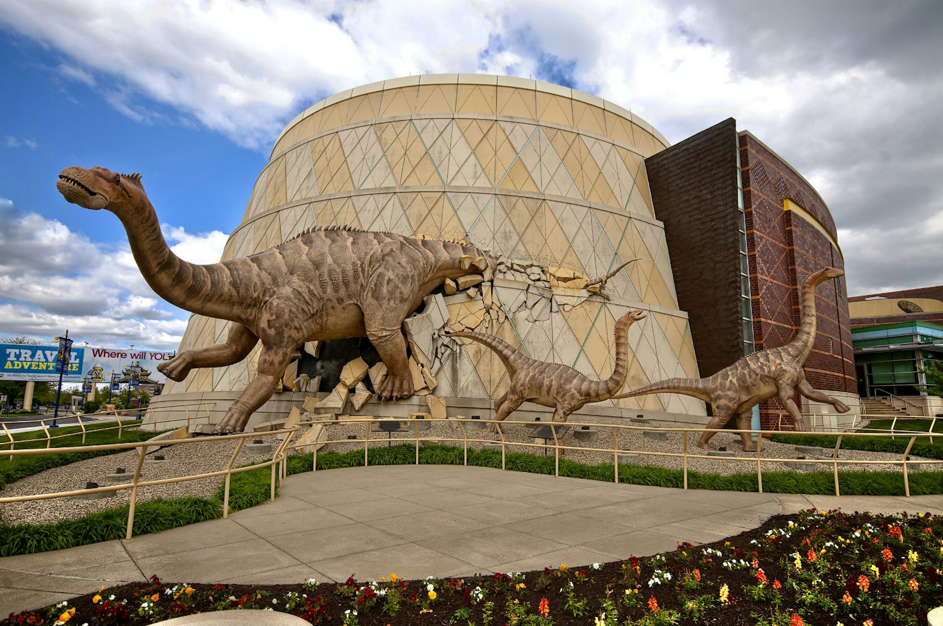 A dinosaur busts through the wall of the Children’s Museum of Indianapolis. Image by Lavengood Photography.