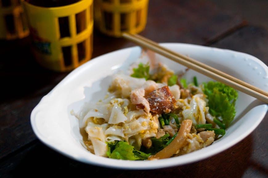 En maträtt med gooay teeo kooa gai, risnudlar stekta med kyckling och ägg, som säljs i Bangkoks Chinatown © Austin Bush / Lonely Planet