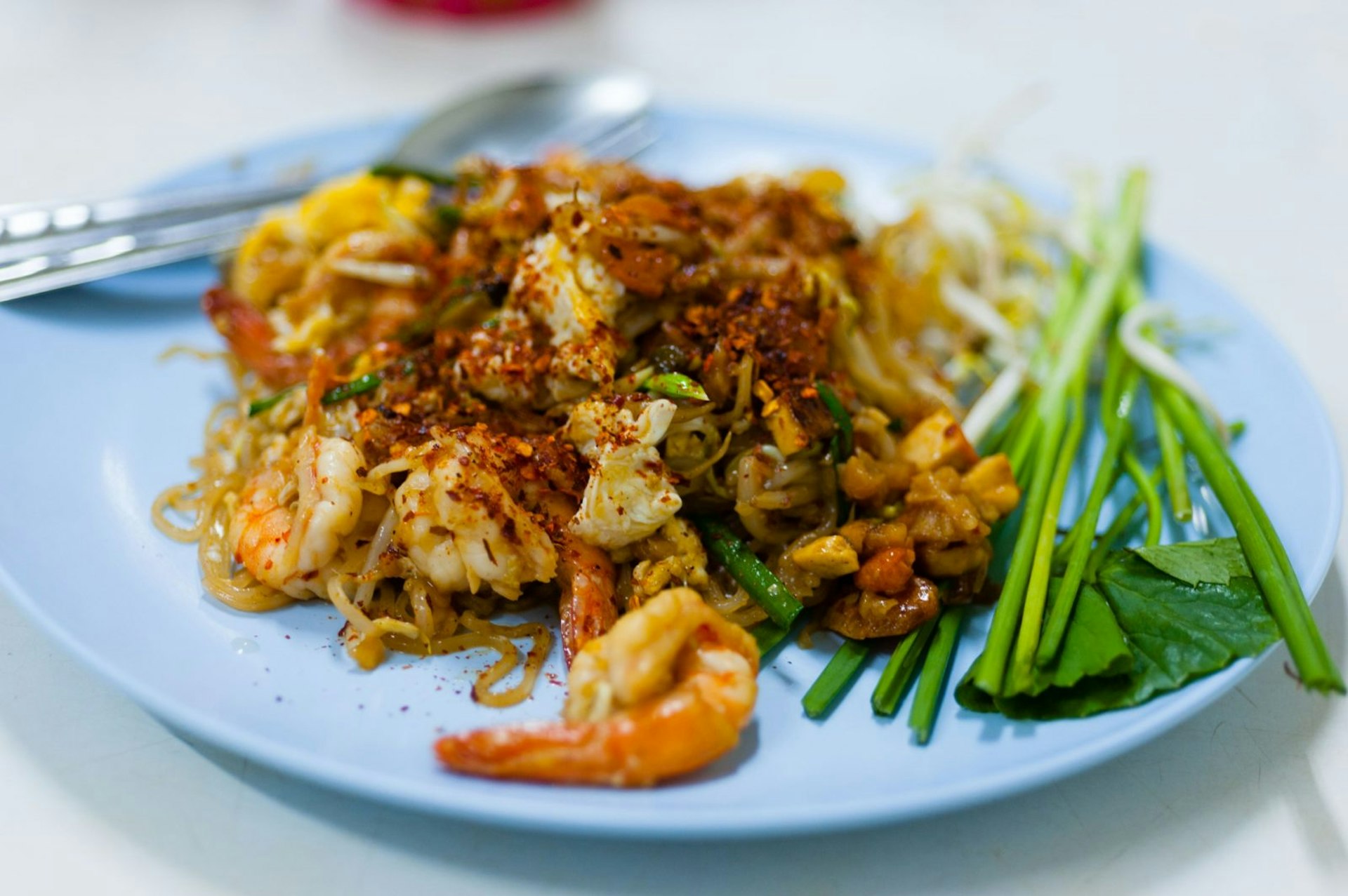 A plate of pat tai, stir-fried noodles with shrimp, bean sprouts, tofu, egg and seasonings from a restaurant in Bangkok, Thailand © Austin Bush / Lonely Planet