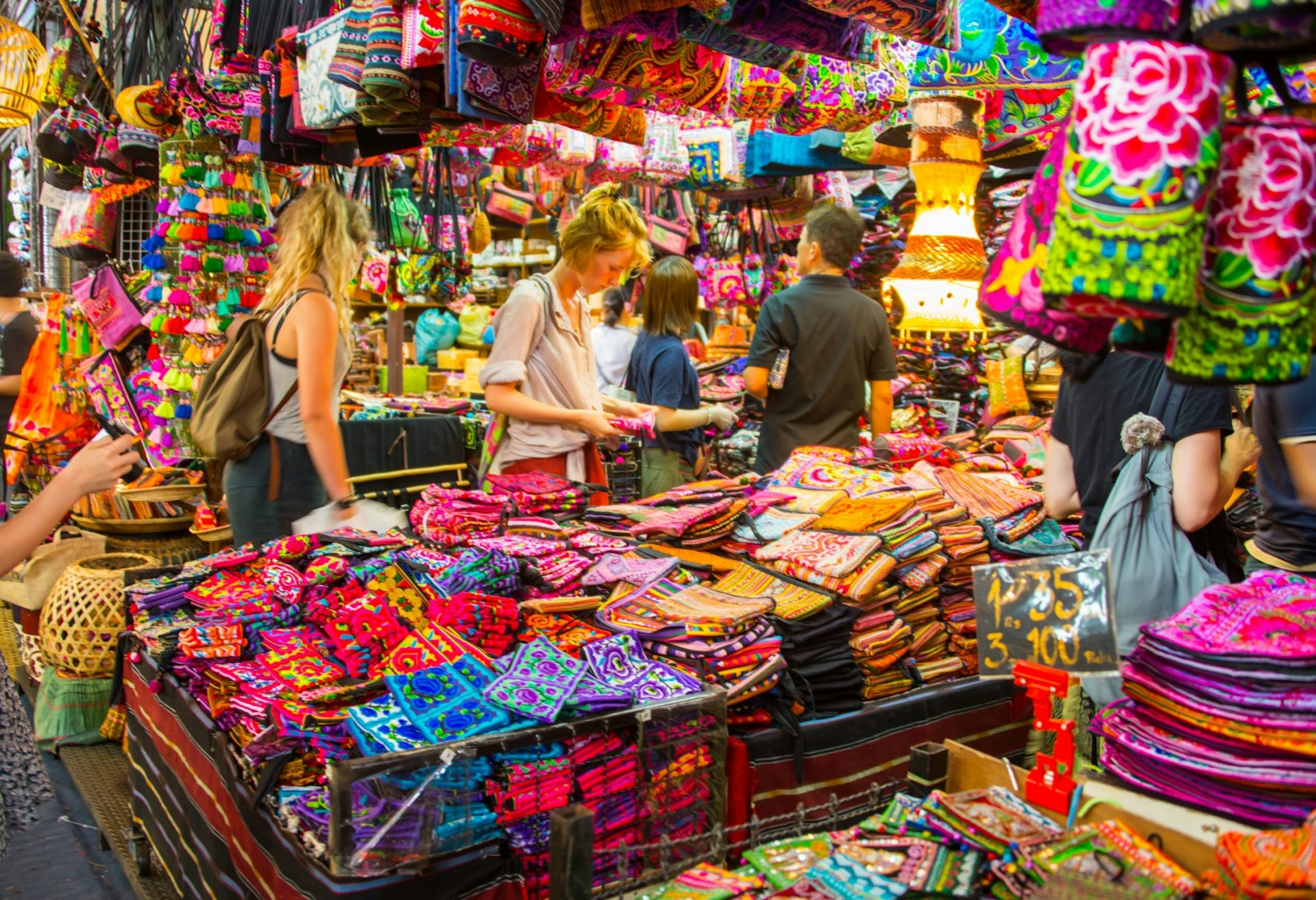 Visitors peruse colourful textiles on offer at Chatuchak Weekend Market in Bangkok © Vassamon Anansukkasem / Shutterstock