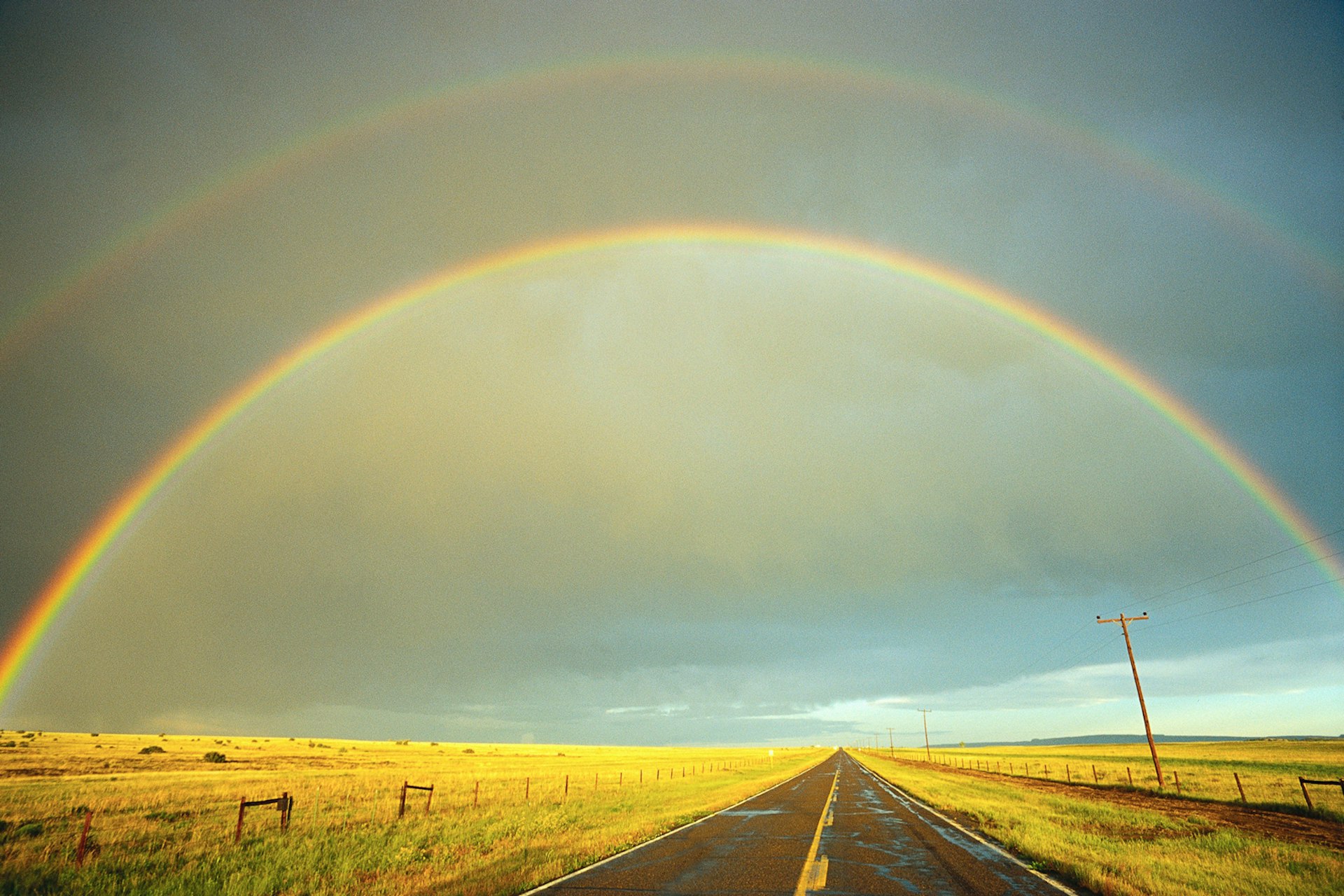 A rainbow stretches over a country road in Kansas