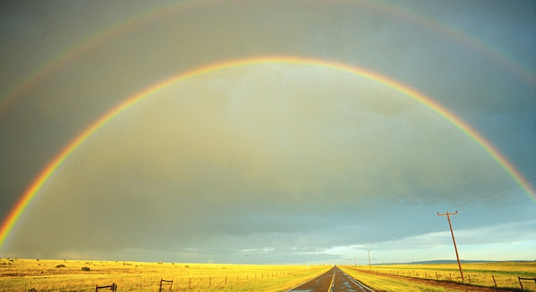 A rainbow stretches over a country road. Image by Fuse / Getty