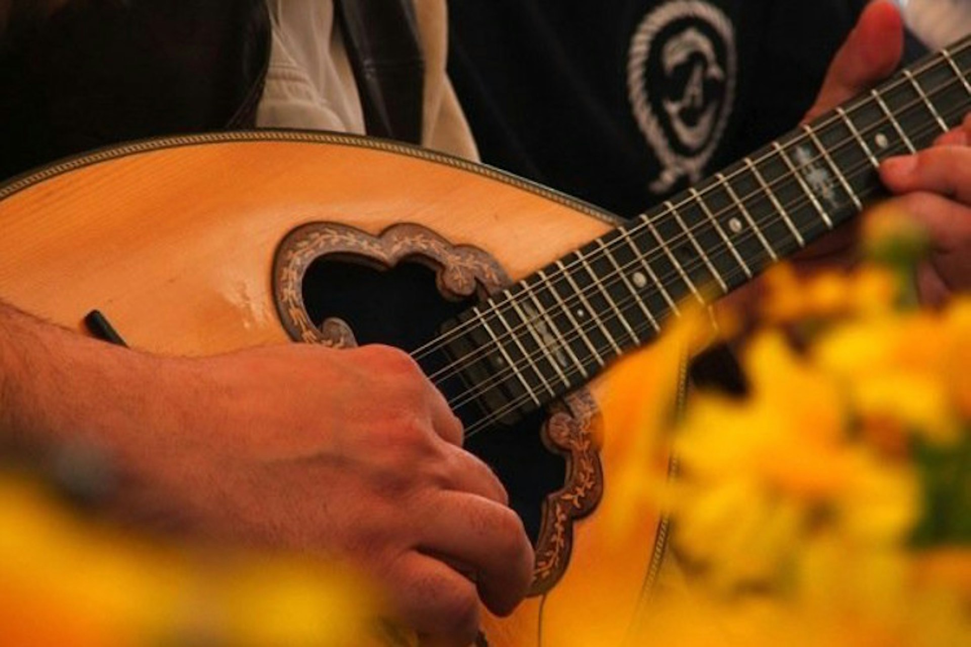 En närbild av en person som spelar ett stränginstrument som kallas bouzouki