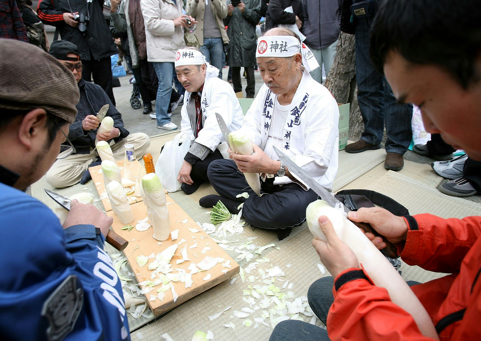 People sit around a table carving phallic shapes out of radishes at the Kanamura Matsuri © Kiyoshi Ota / Getty Images