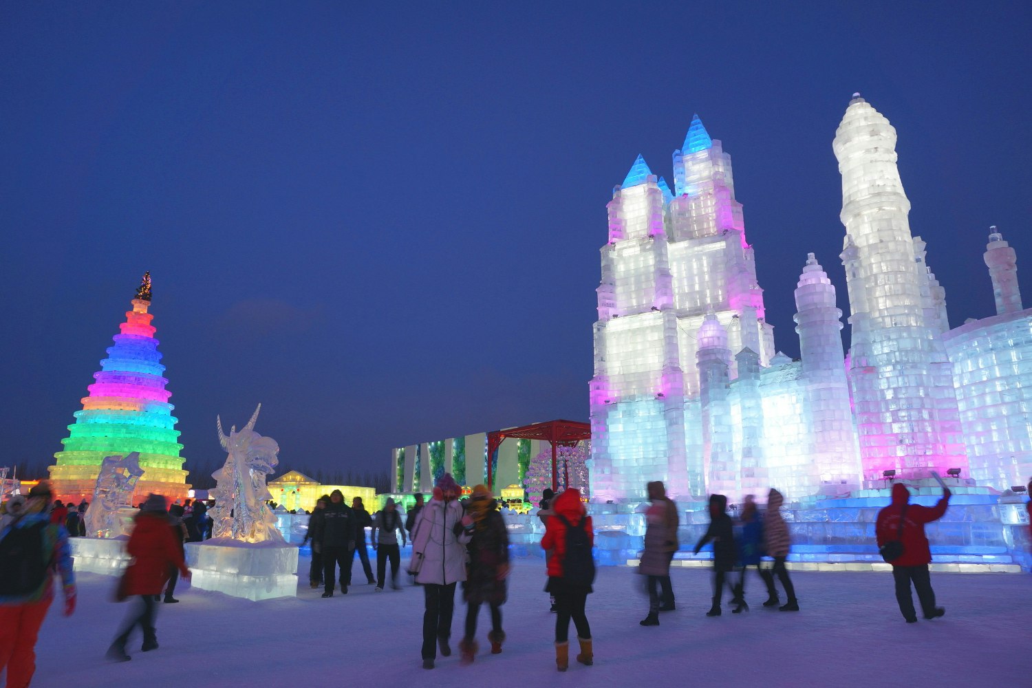 Crowds mingle around colourful ice towers within Harbin's Ice and Snow World