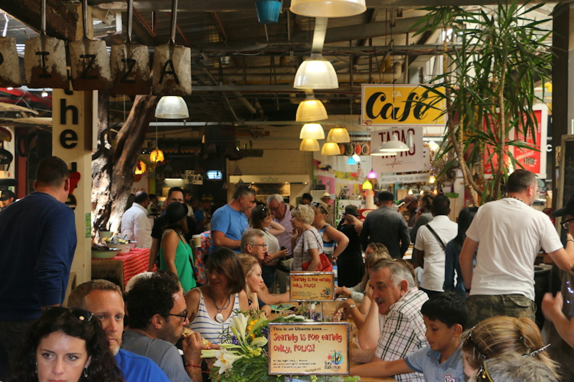 Crowds sit around tables and peruse goods in a very warm atmosphere.