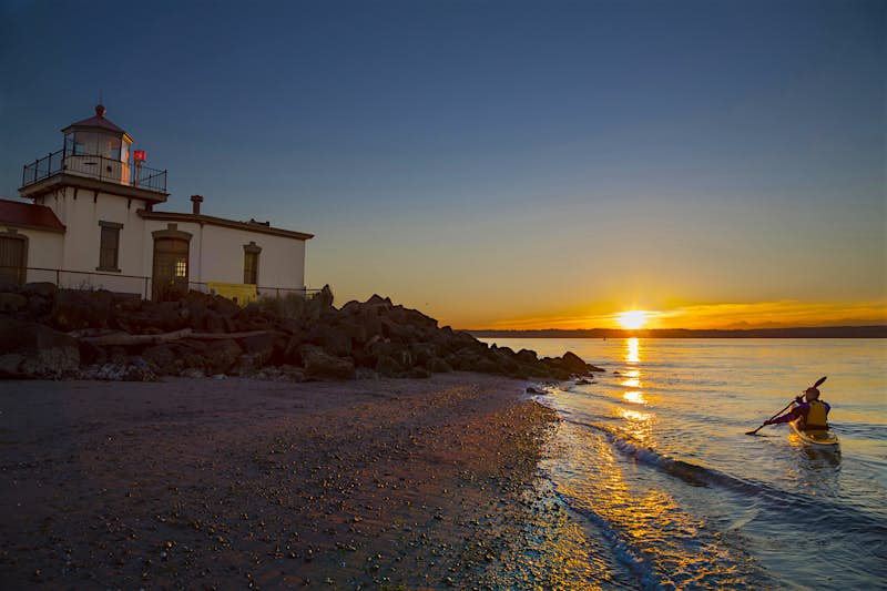 Features - 513053503_11-rs A kayaker takes a sunset trip near the West Point Lighthouse in Discovery Park. Image by Danita Delimont / Gallo Images / Getty