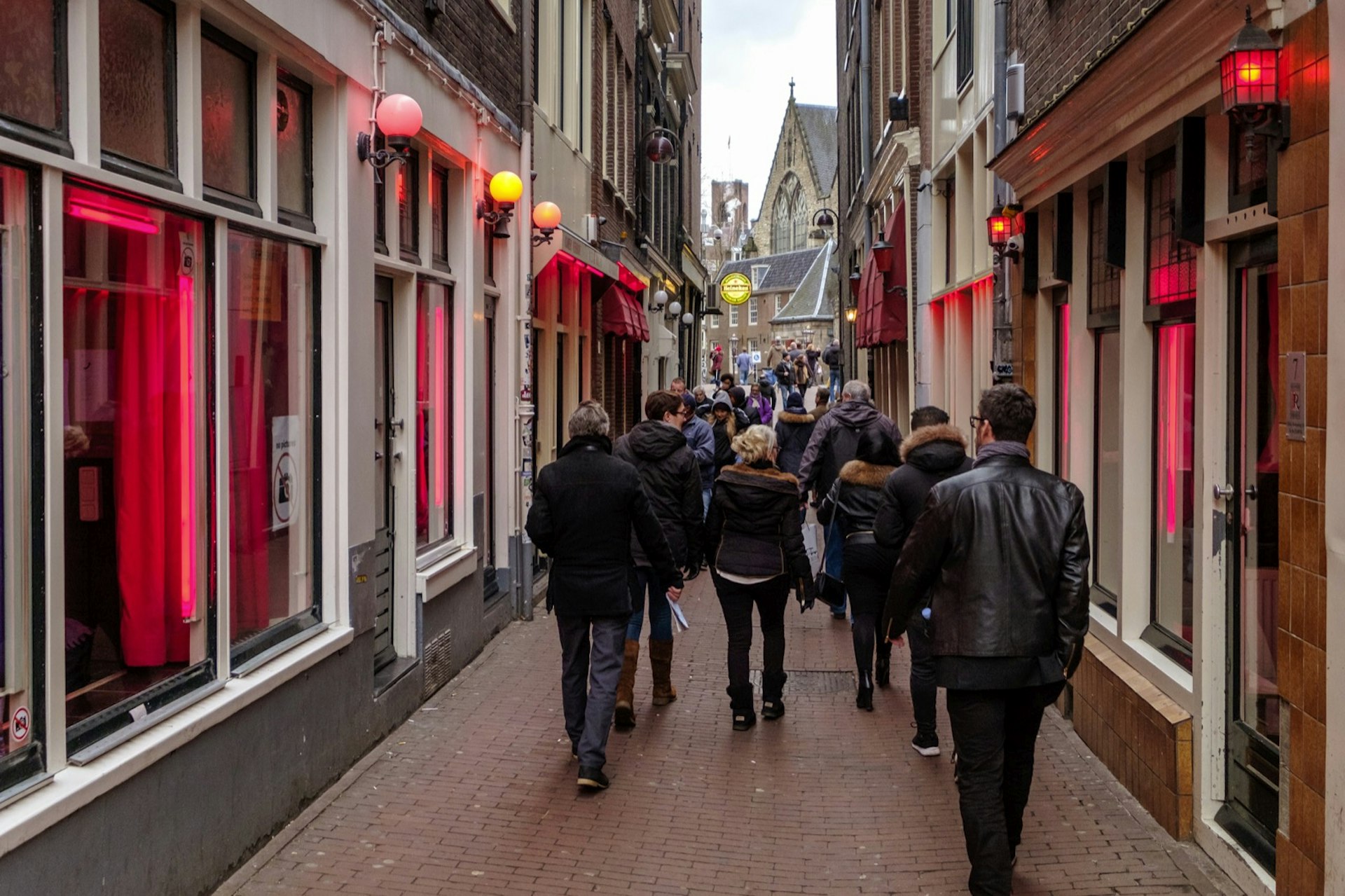 Tourists walking in the red light districts, where prostitutes try to lure customers from behind their windows.