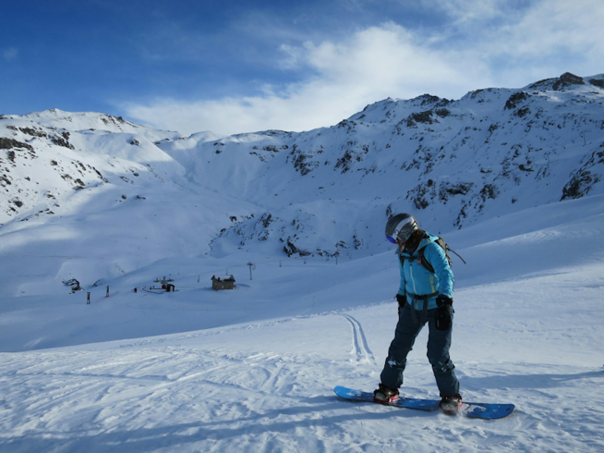 A snowboarder rides off-piste to a chair lift, La Plagne, French Alps.
