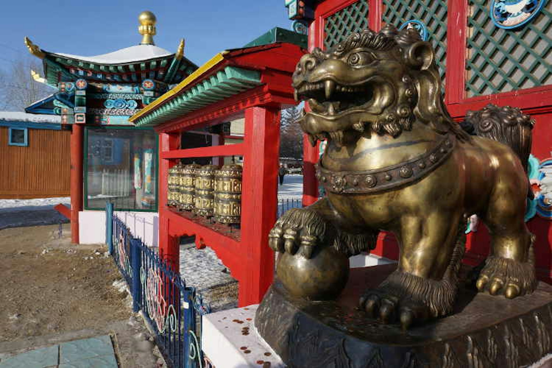 Bronze lion and prayer wheels outside a temple