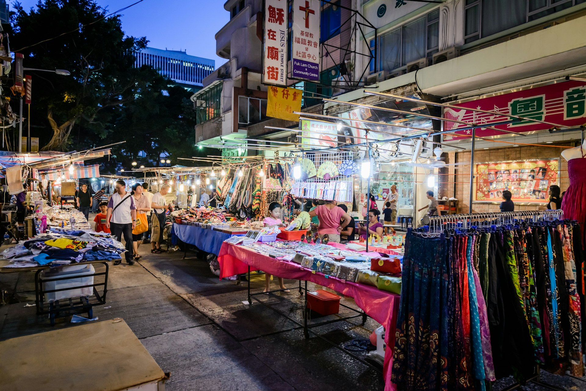 Shopping stalls line a road in Mong Kok; people walk between the tables. Hong Kong.