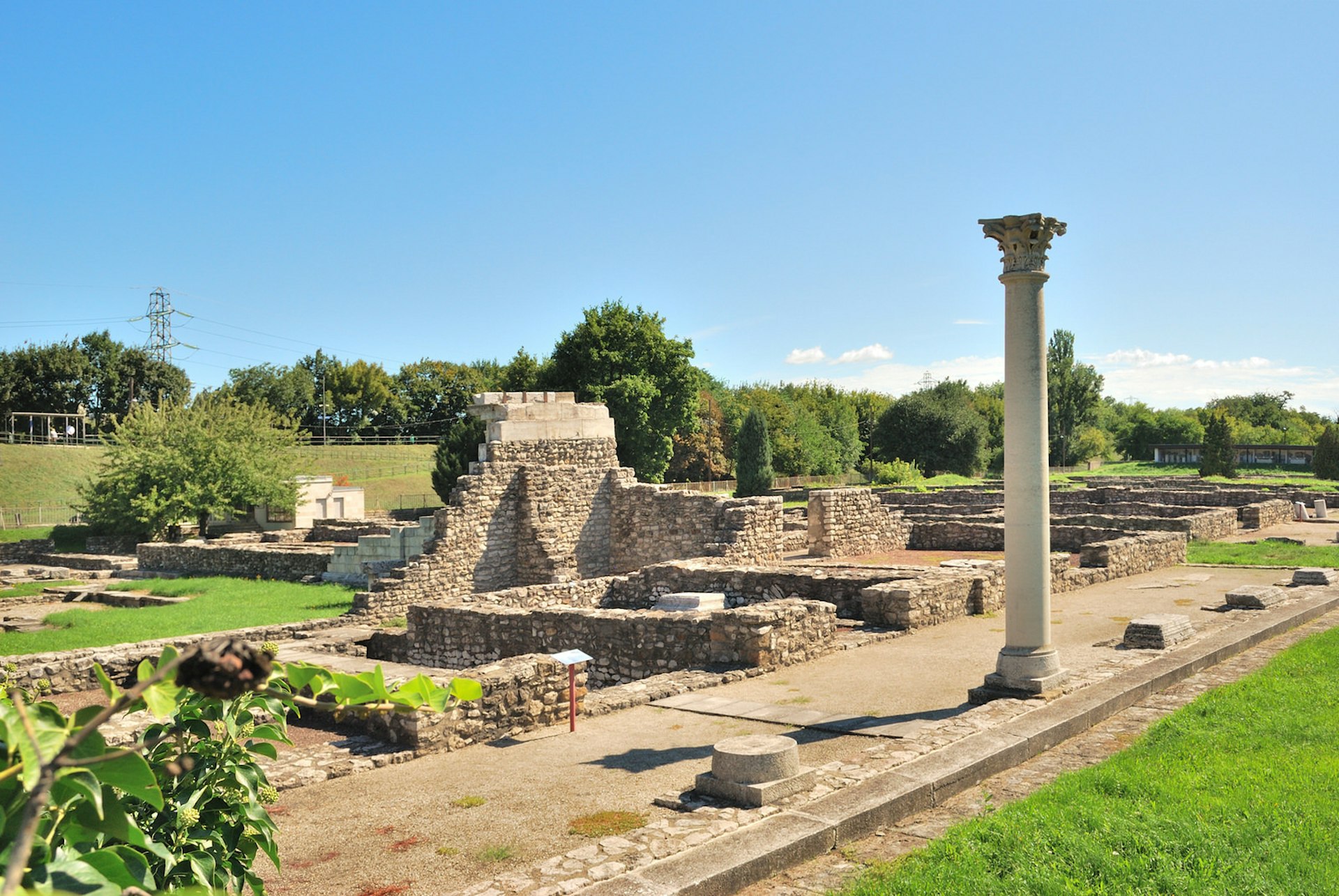 The ruins of the Aquincum Roman baths, a collection of small walls and pillars standing in a green field in Budapest, Hungary