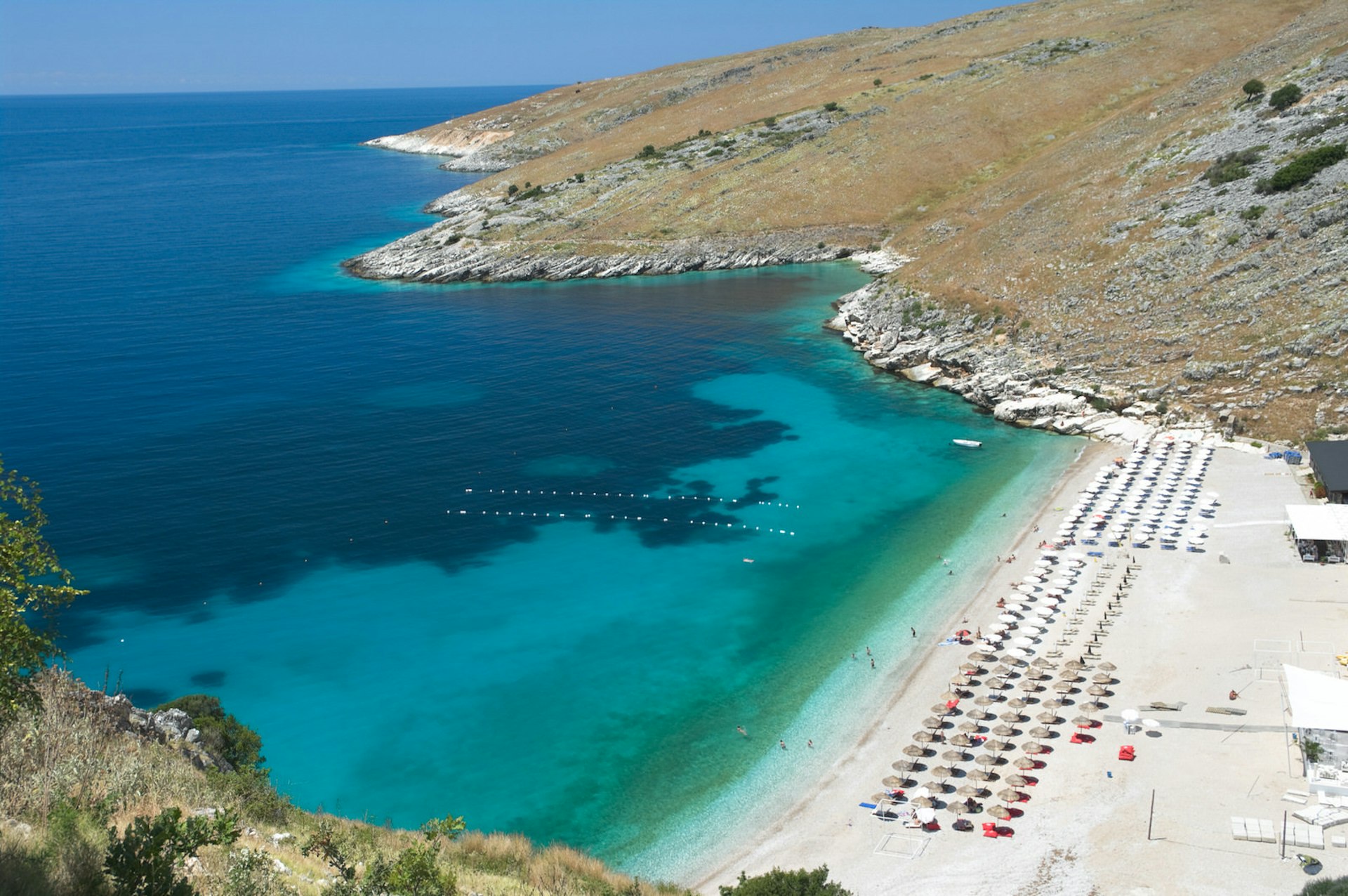 High-angle view of Llamani Beach near Himare with rows of sun loungers lining the sand