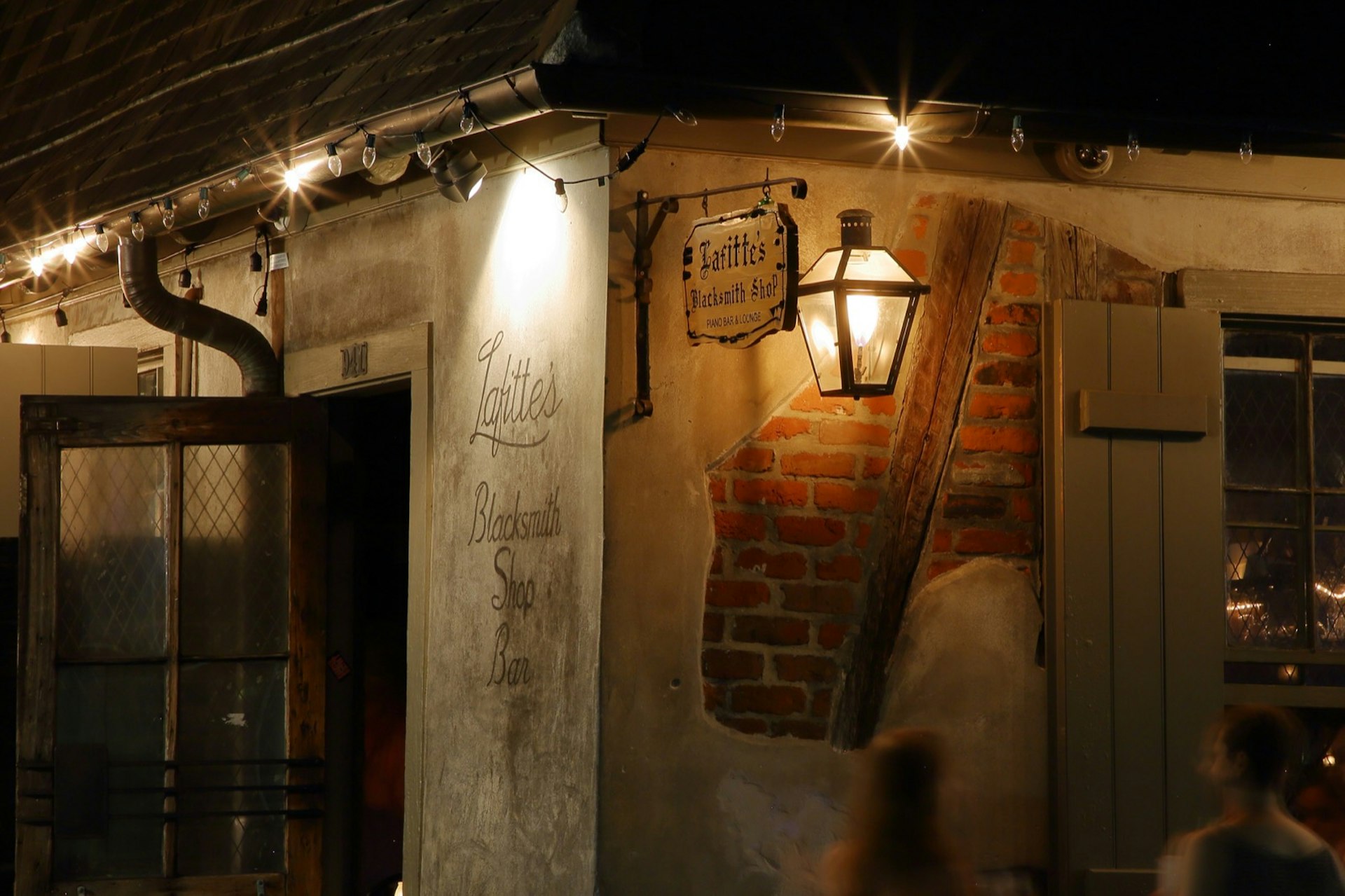 A lighted lantern hangs next to a light wooden sign and exposed red brick at the historic Lafitte's Blacksmith Shop, a famous bar that has been around since the 1700s. There's no shortage of activities for a lively New Orleans weekend. 