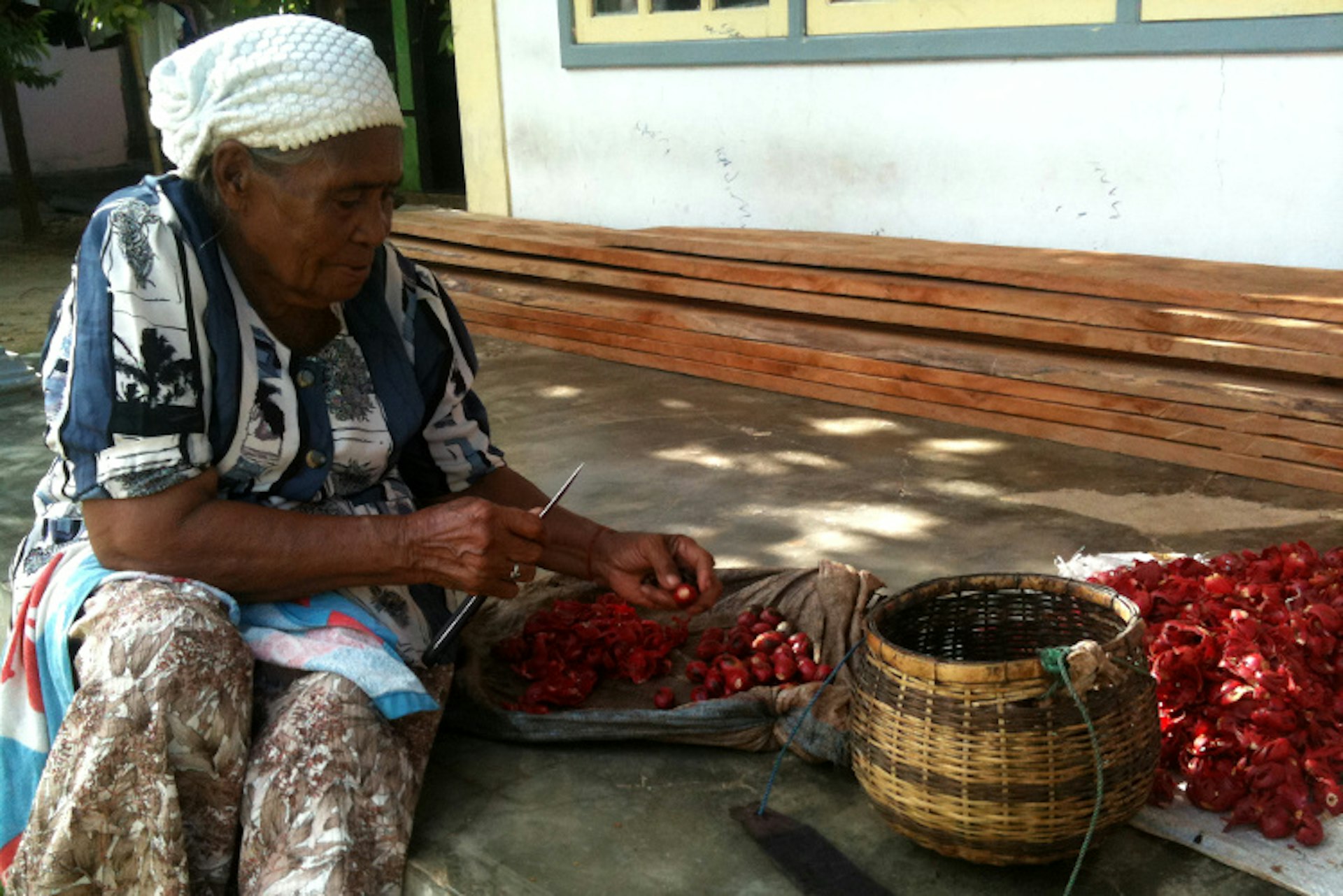 Vllage elder separating nutmeg and mace for drying, Maluku. Image by Hugh McNaughtan