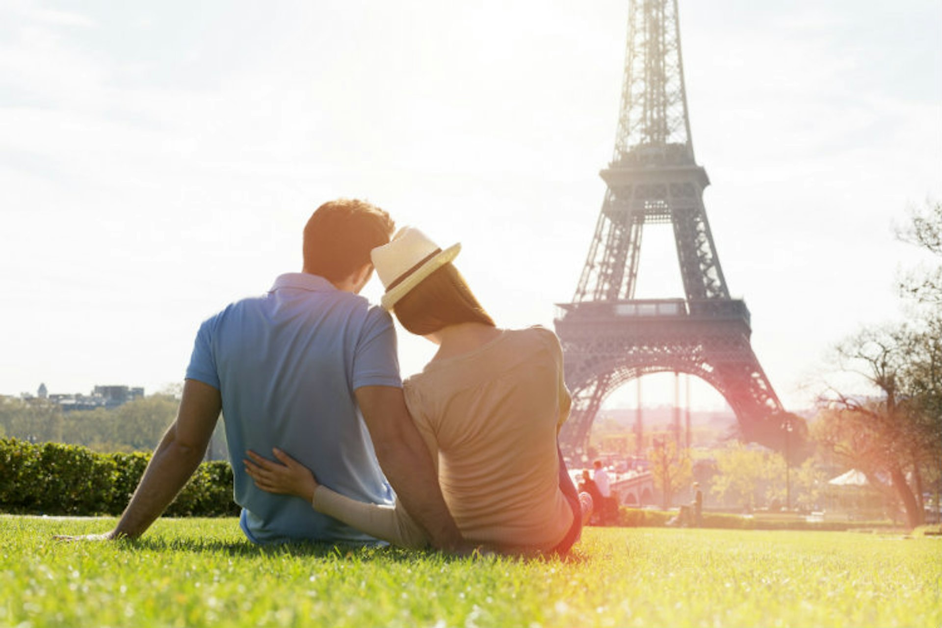 A couple sitting on grass overlooking the Eiffel Tower, Paris