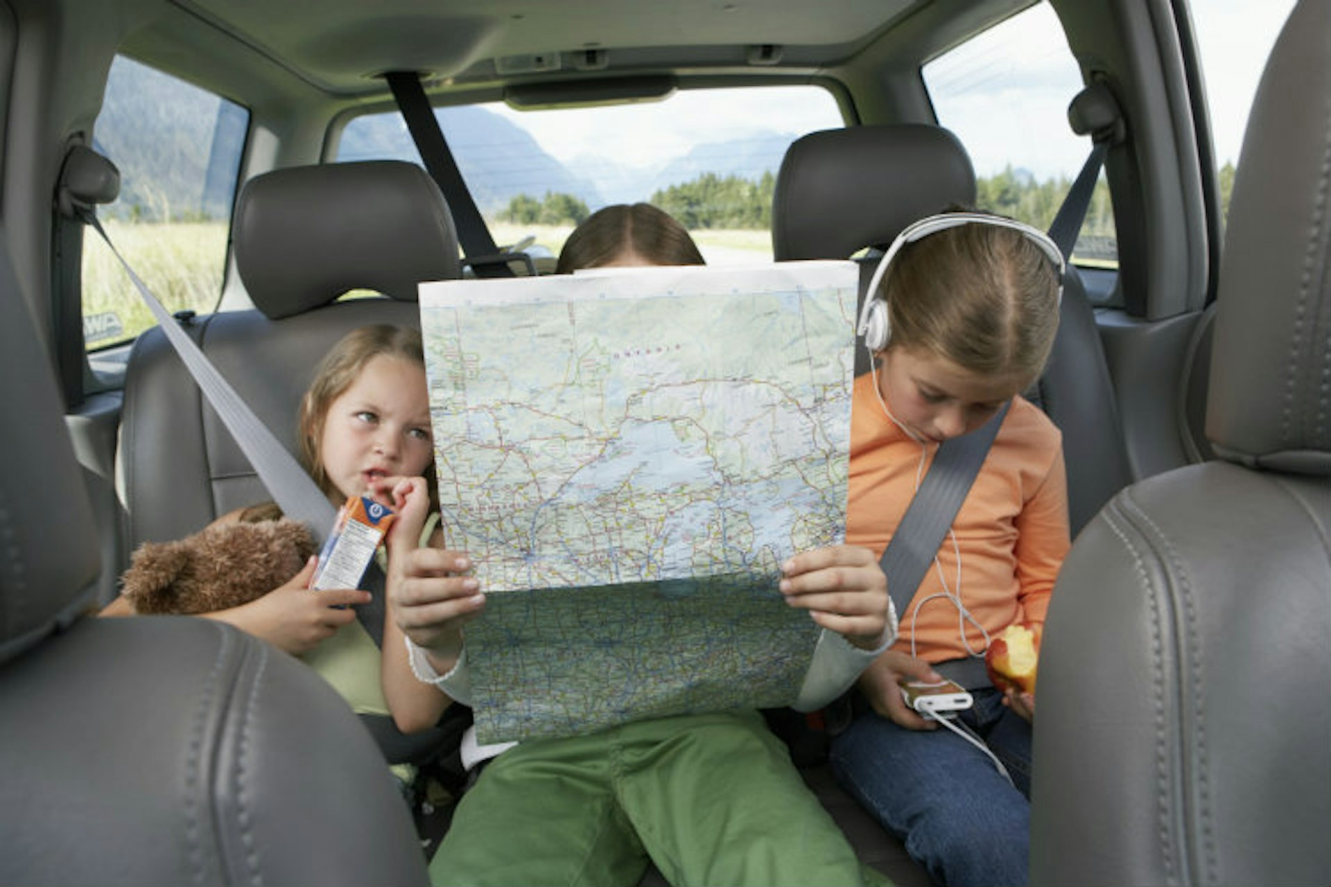 Three girls (6-8 years) sitting on rear seat of car on road trip