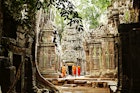 Features - Monks wandering through temple ruins of Ta Prohm.