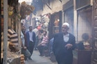 Features - Man walking through alleyway lined with food stalls in Souq El Attarine.