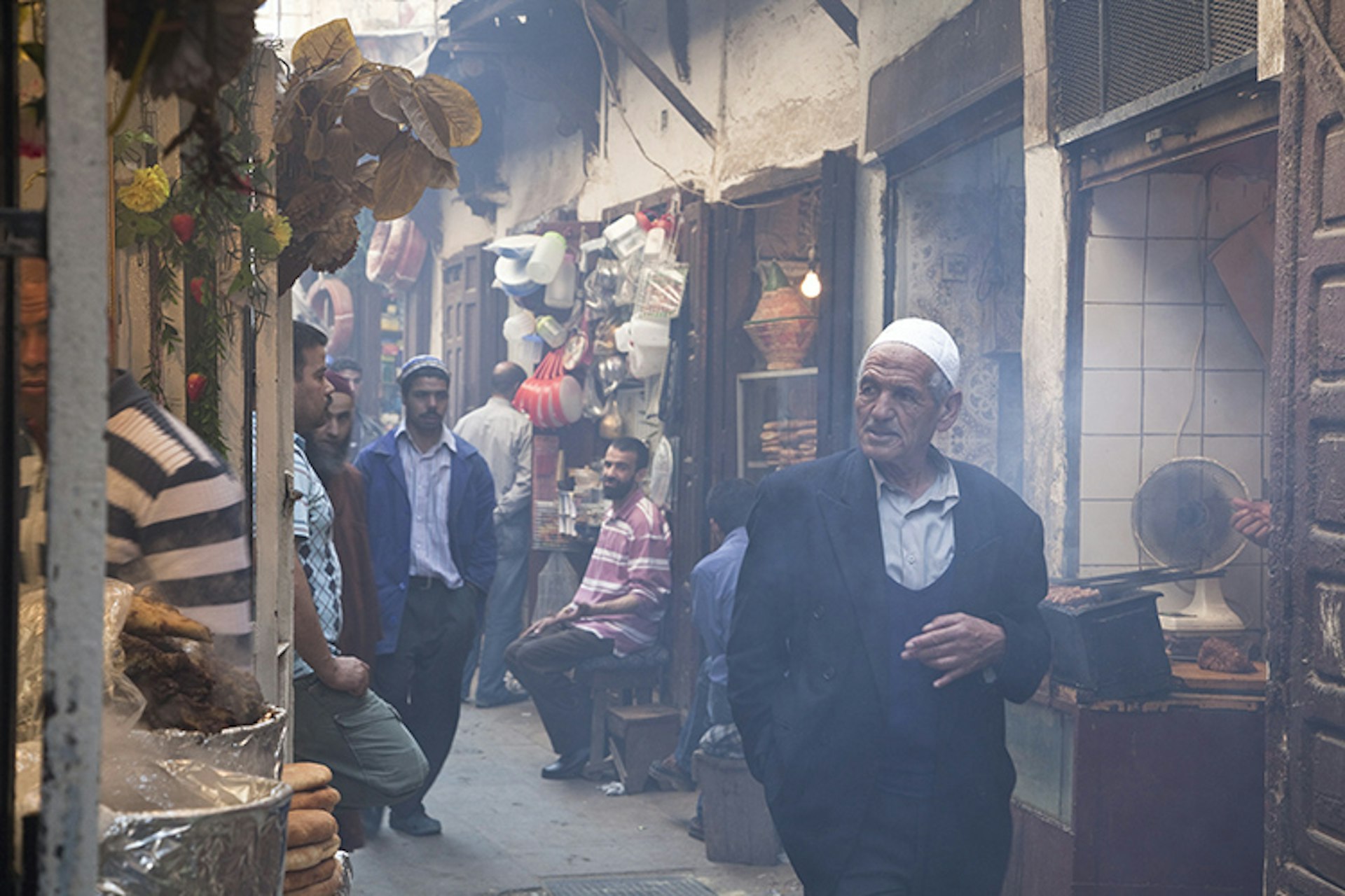 Man walking through alleyway lined with food stalls in Souq El Attarine.