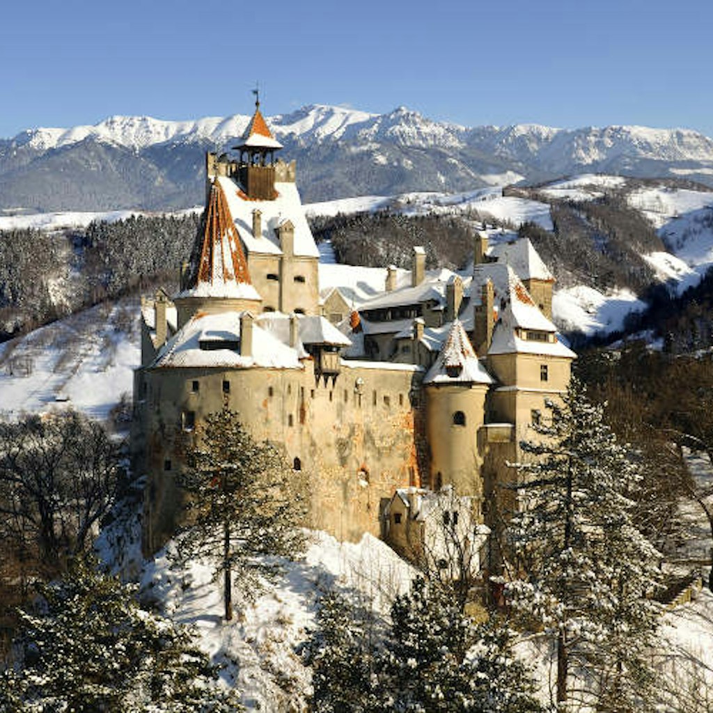 Snow-covered Bran Castle and Bucegi Mountains. Image by warmcolors / iStock / Getty Images