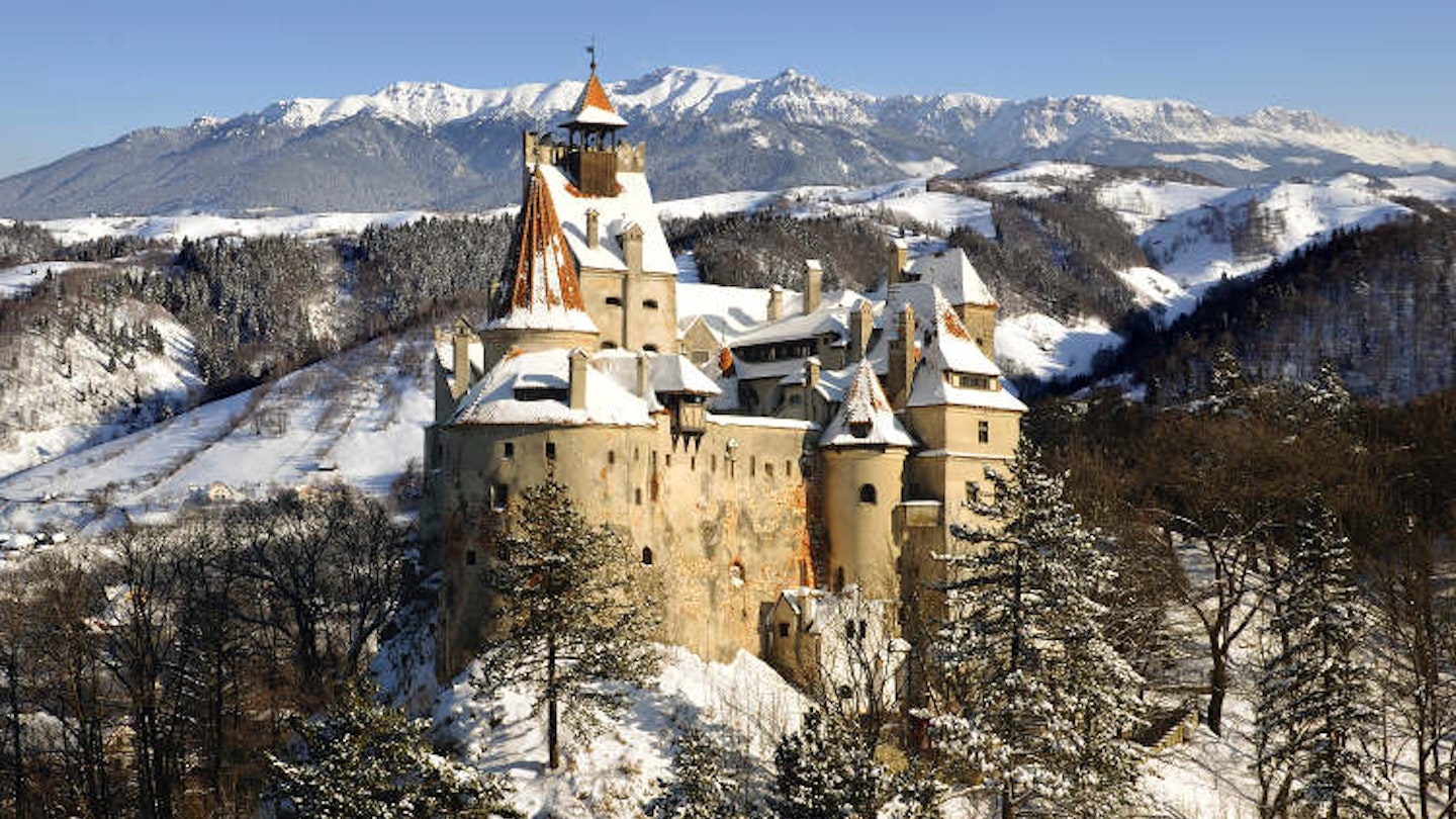 Snow-covered Bran Castle and Bucegi Mountains. Image by warmcolors / iStock / Getty Images