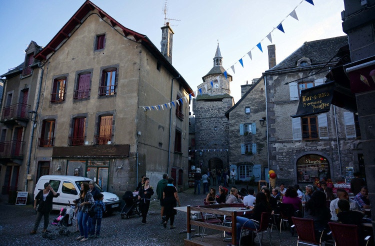 Besse-et-Saint-Anastasie's brasseries and old town shops overlooked by the historic town belfry. Image by Anita Isalska