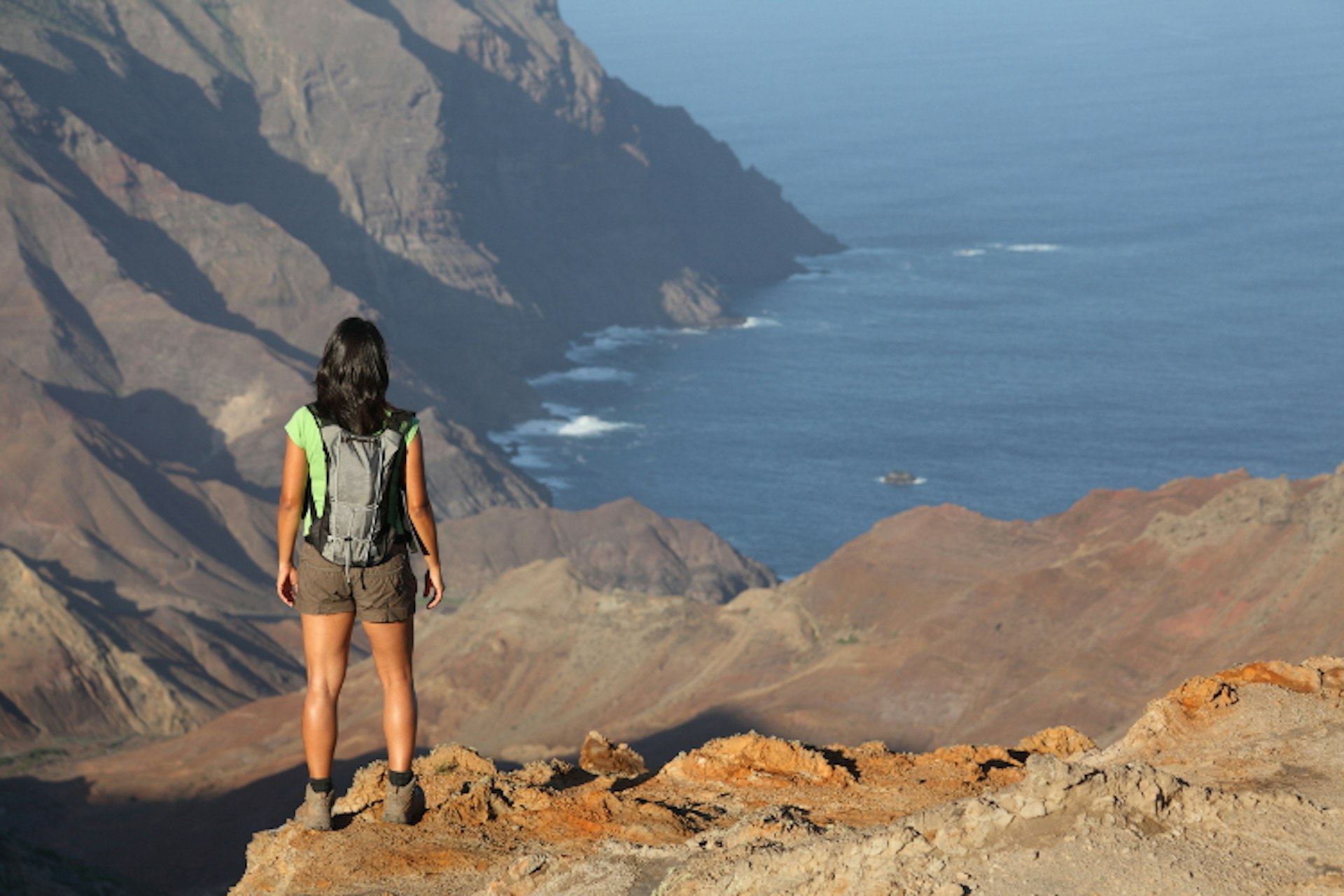 Hiker looking down to Sandy Bay, St Helena. Image by Darrin Henry / Lonely Planet