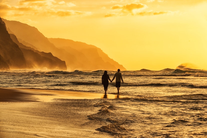 A couple walks along the beach on Kaua‘i. Image by Justin Horrocks / Getty