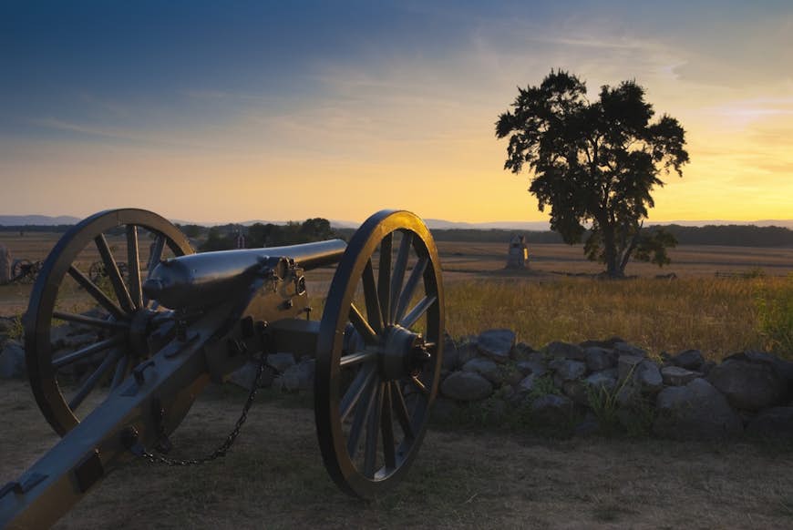 A cannon is pointed across a field at sunset. Gettysburg is an important site of US History.