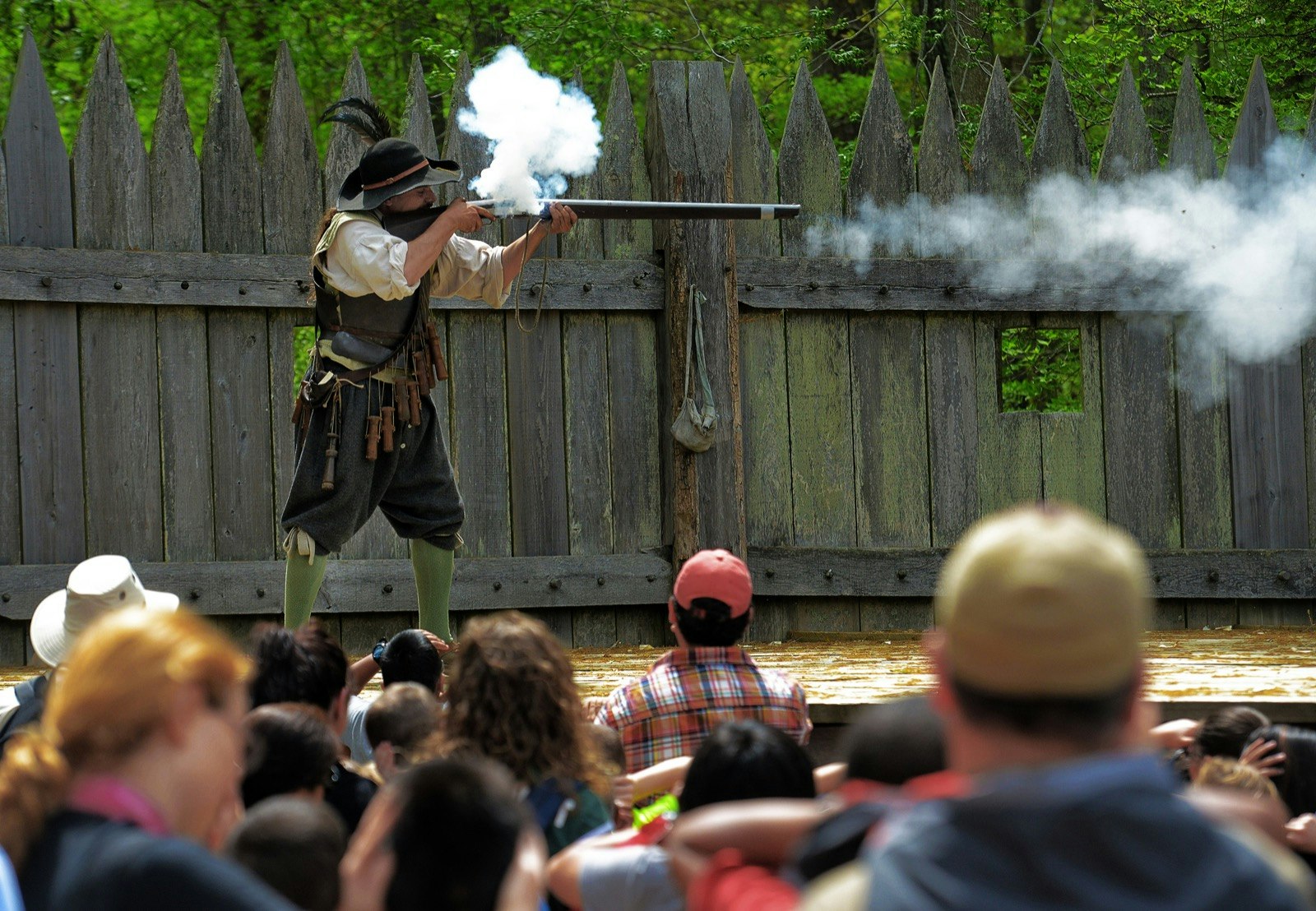 A man dressed in period dress fires a gun as spectators look on at Jamestown Settlement, one of the most important sites of history in the US