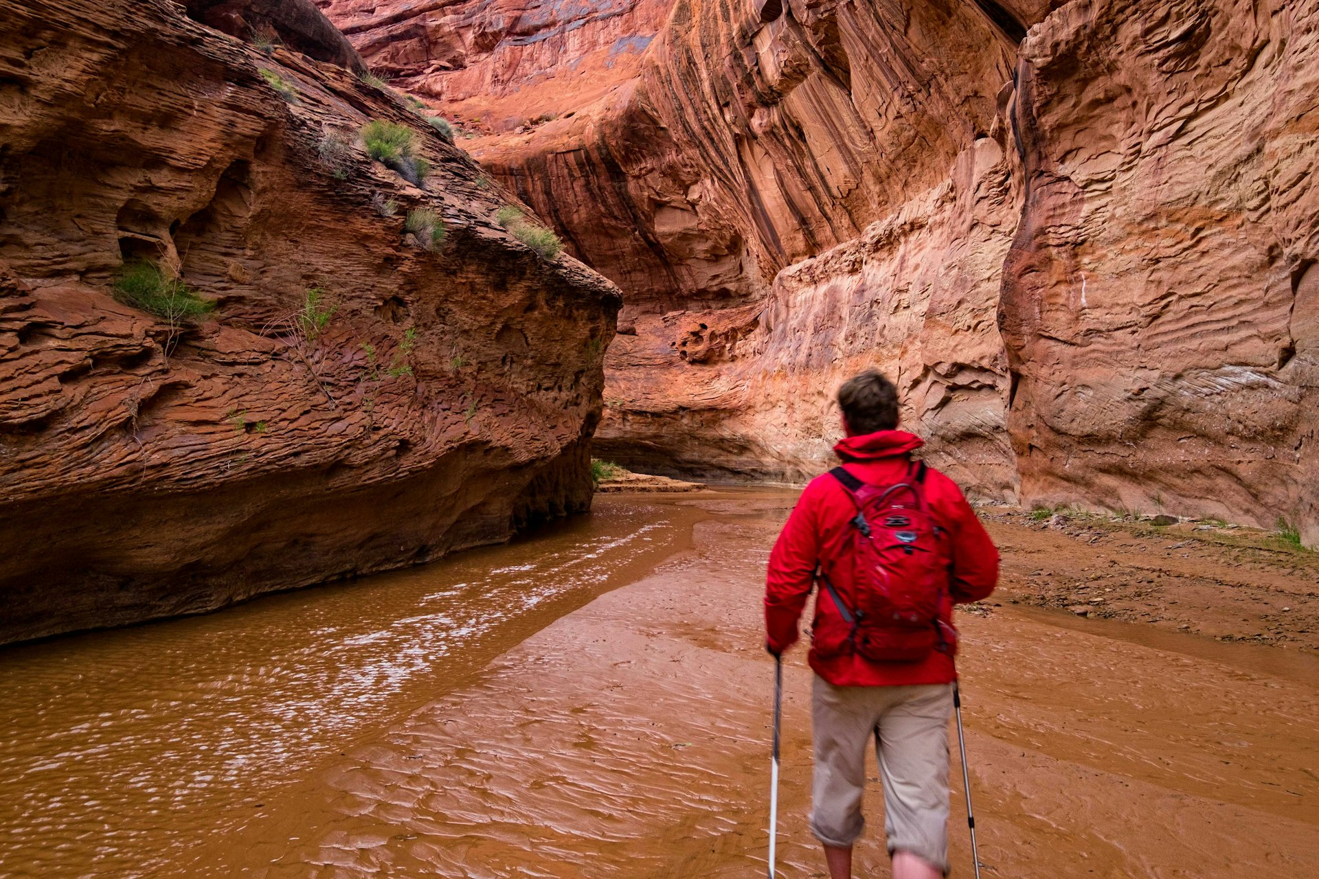 A man hiking through the red-rock walls of a slot canyon. Image by Adventure_Photo / E+ / Getty