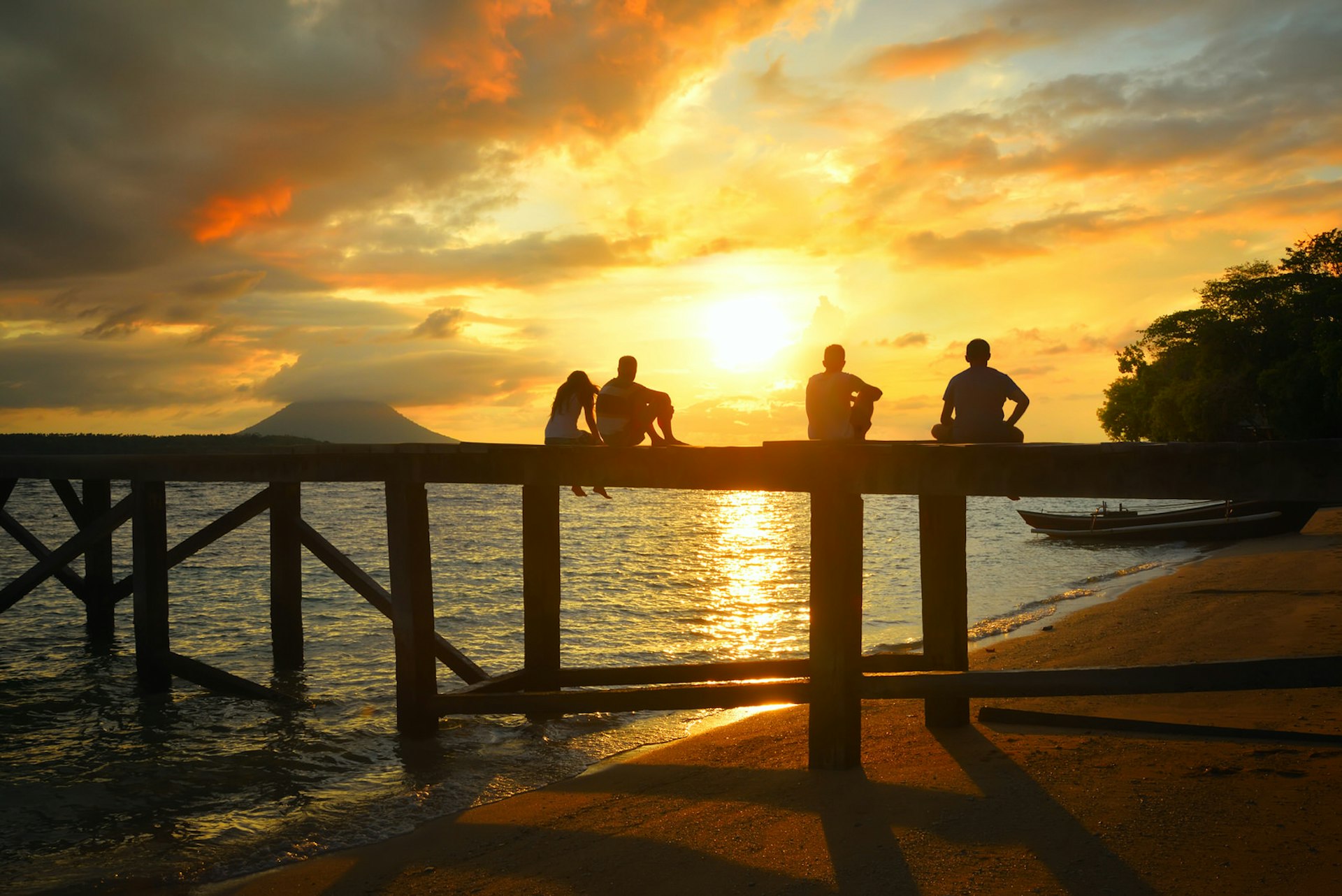 A group of travellers sit on a pier at sunset © soft_light / Shutterstock