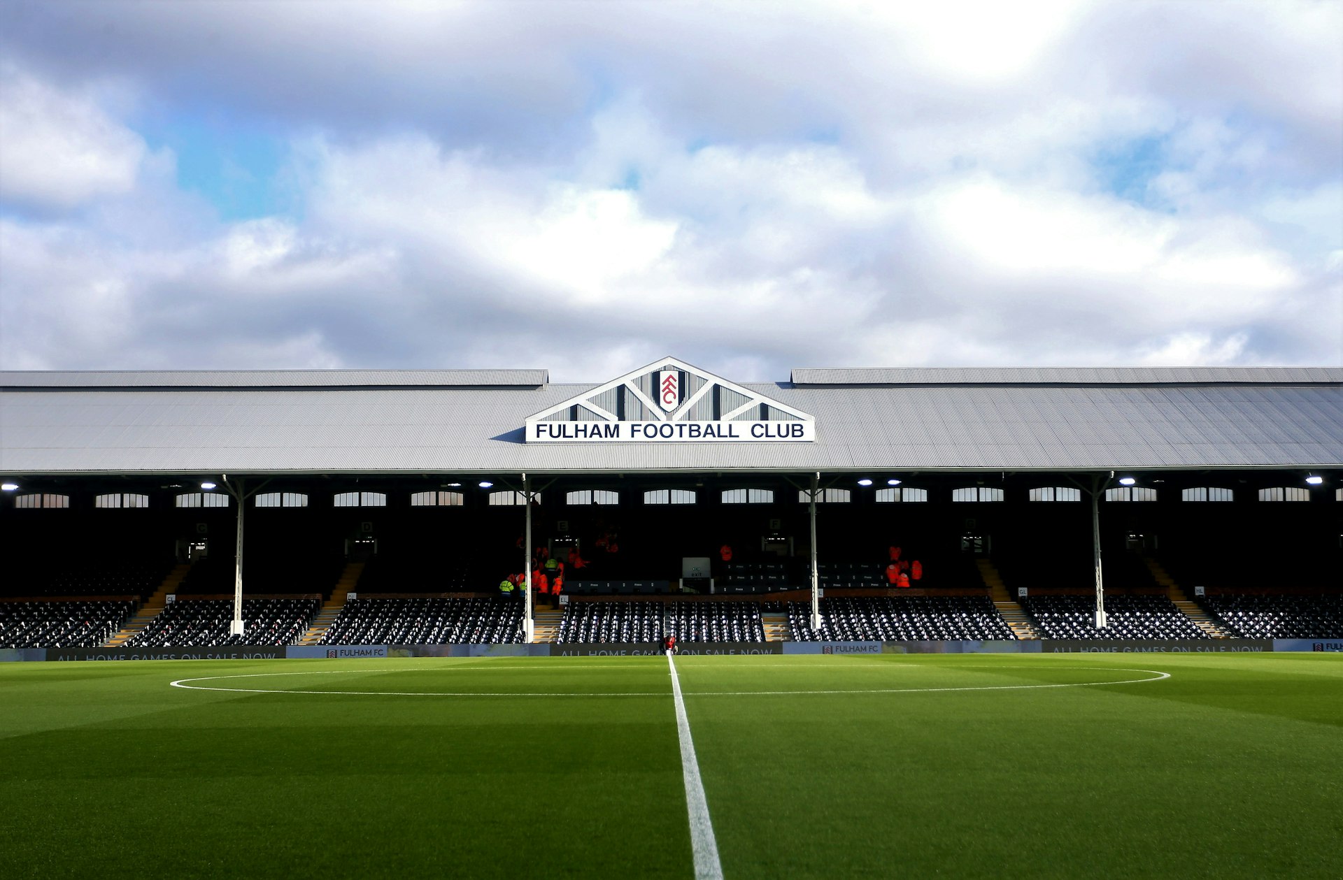 Craven Cottage football ground on a slightly overcast day. The football pitch and stands are empty and the vibrant green grass looks perfect. 