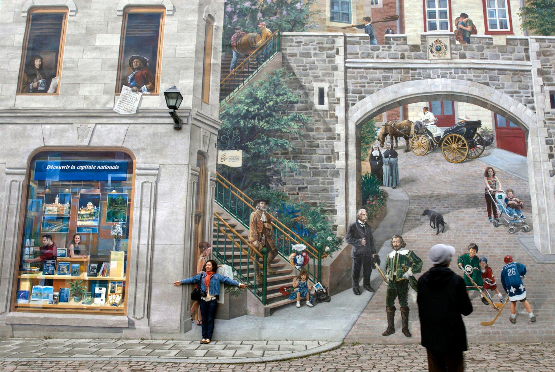 A woman poses in front of the giant Fresque des Québécois which tells the story of Québec City’s history