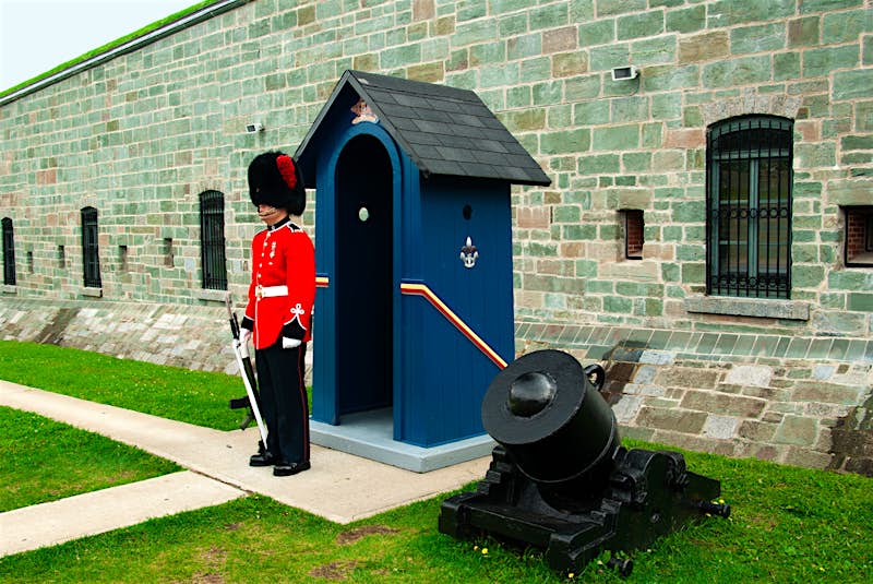 Citadelle guard, Québec City A guard with a sword in a red uniform and beaver hat stands watch at the Citadelle outside a blue shed