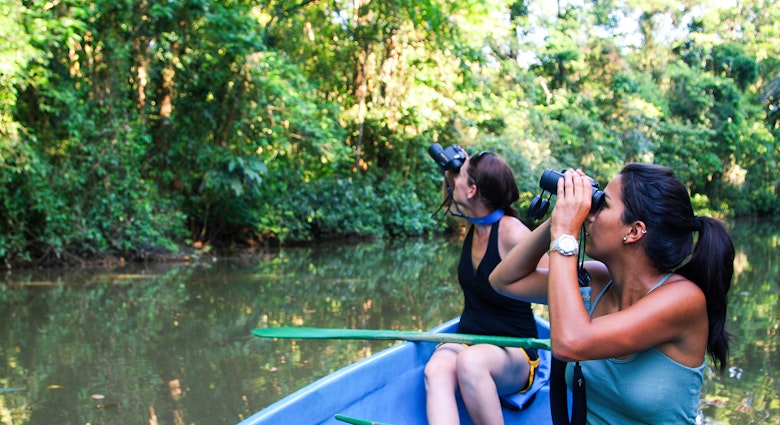 Features - Eco-tourists on boat tour through rainforest.