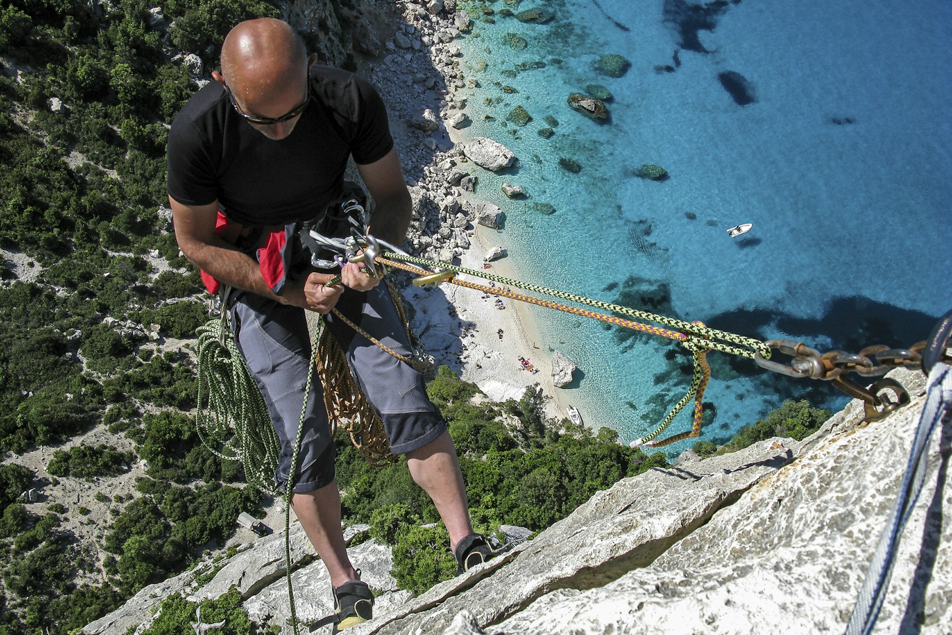 A man abseils down a cliff to Cala Goloritzè from Aguglia in Sardinia.