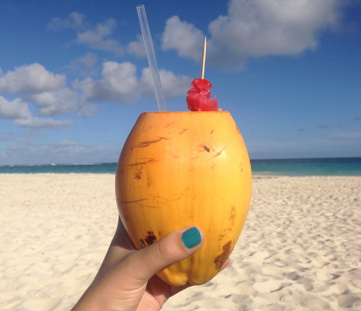 Features - Coconut rum cocktail served on the beach in Barbados. Image by Sarah Reid_cs