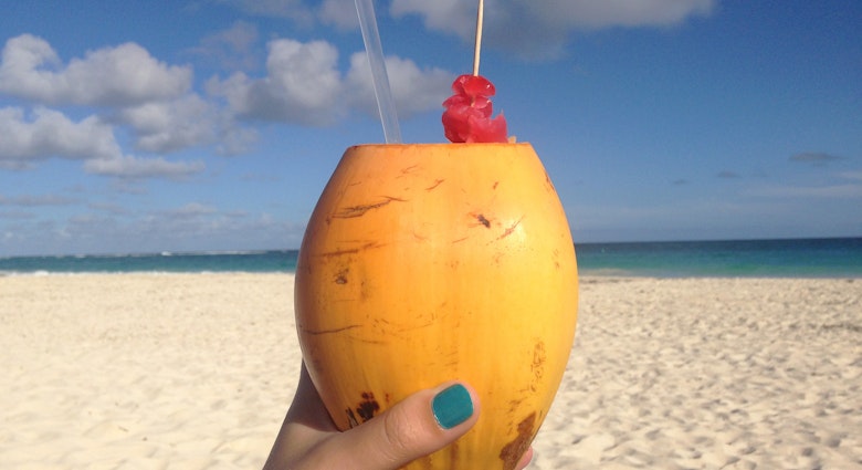 Features - Coconut rum cocktail served on the beach in Barbados. Image by Sarah Reid_cs